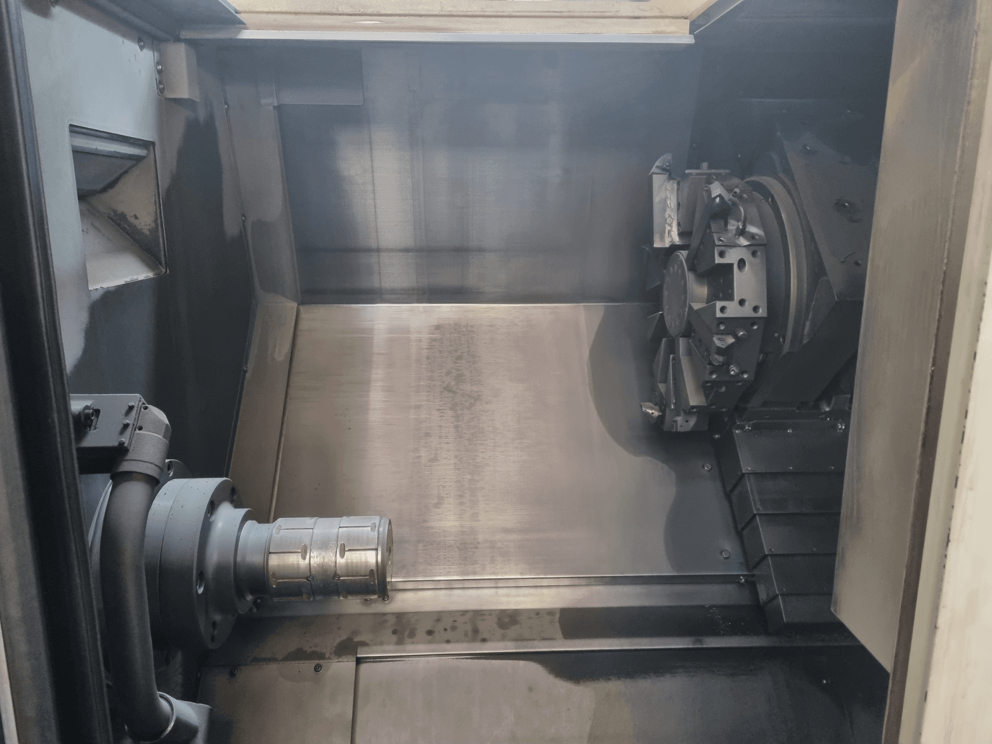 Invändig vy av en CNC-maskin som visar ett arbetsområde i metall, verktygshållare och chuck; betonar precisionsteknik.