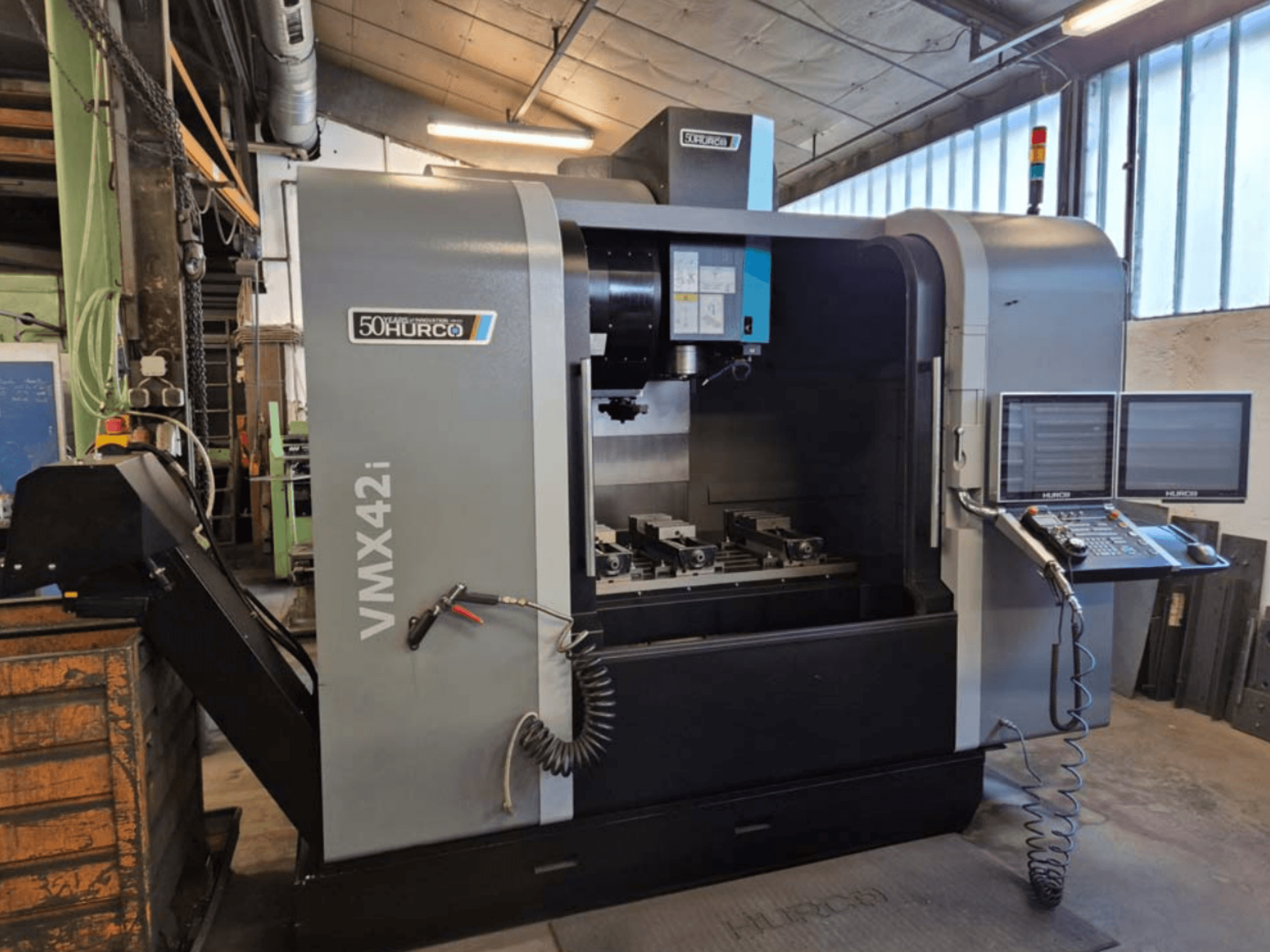 Hurco VMX 42i vertikal fleroperationsmaskin, vy framifrån, med kontrollpanel och arbetsområde med skruvstycken.