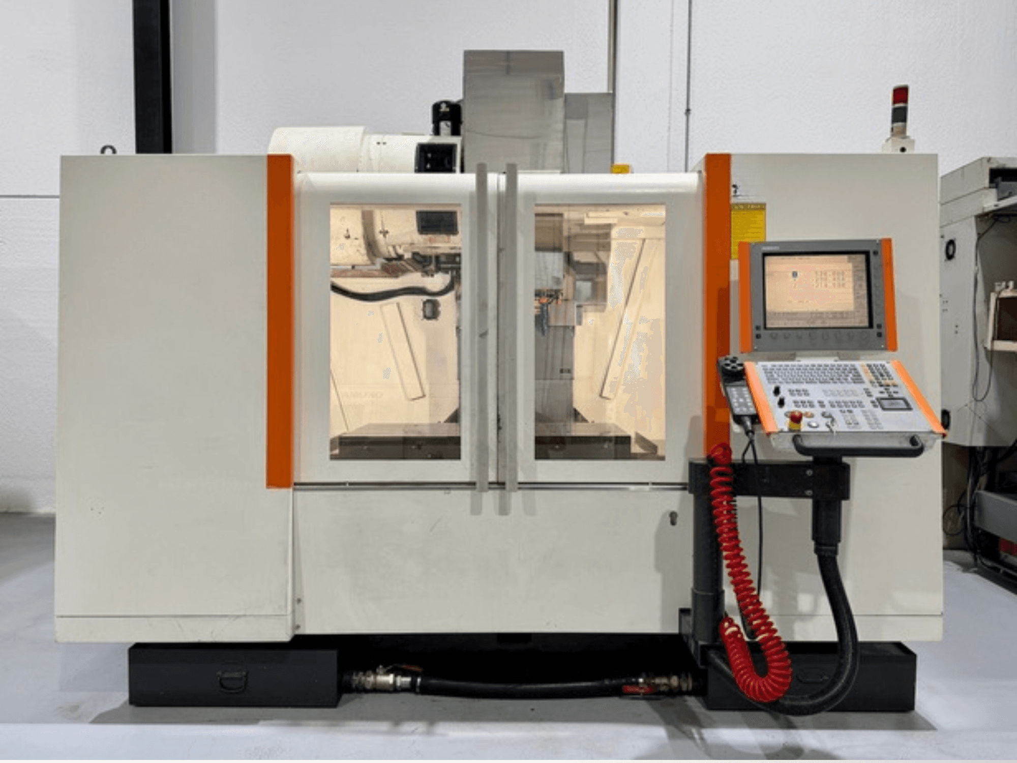 CNC-maskin med orangefärgade detaljer, vy framifrån. Innehåller kontrollpanel och synligt inre arbete.