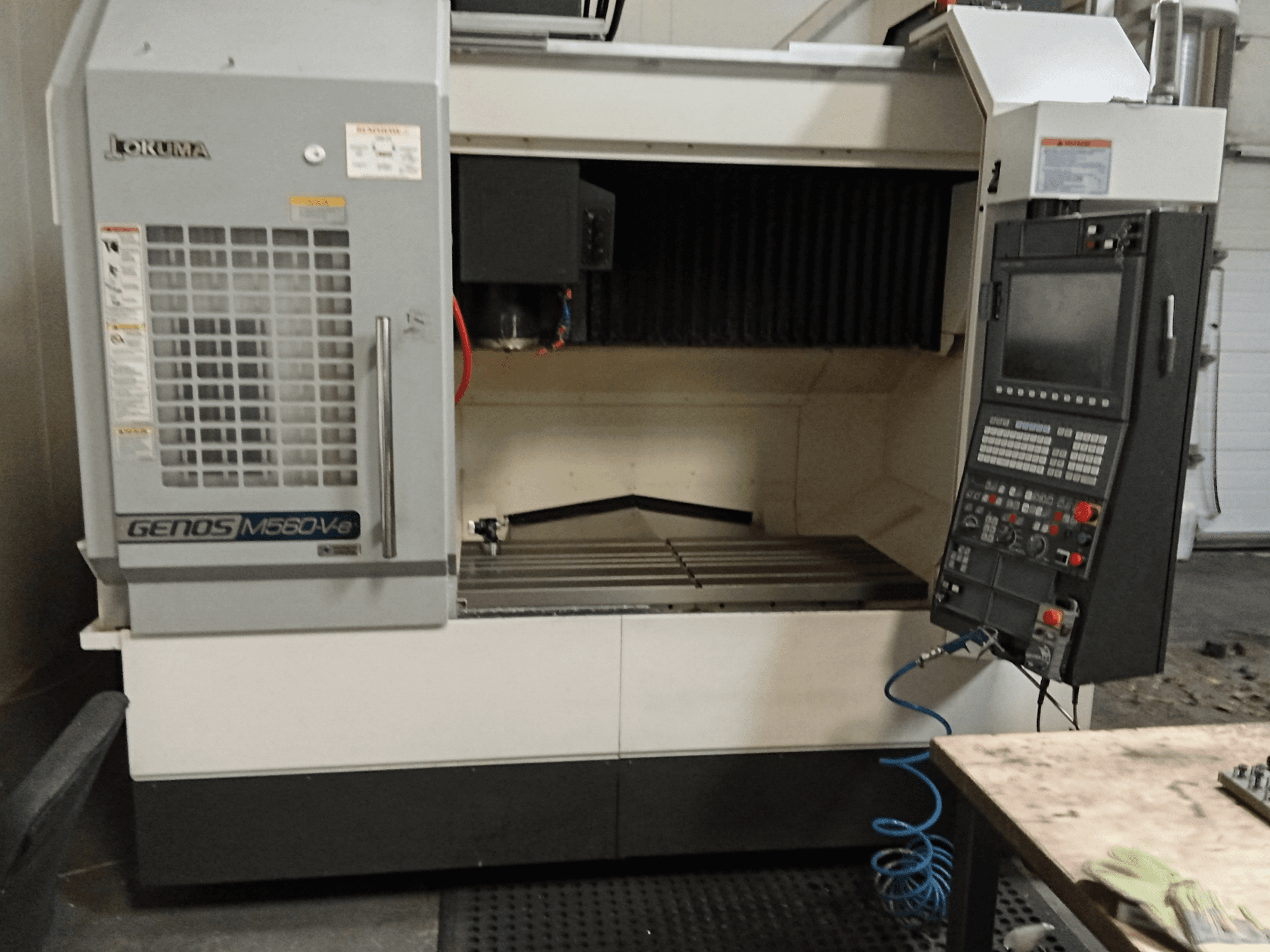 Okuma GENOS M560-V, frontvy av ett vertikalt bearbetningscenter med kontrollpanel, CNC-gränssnitt och synligt skärområde.