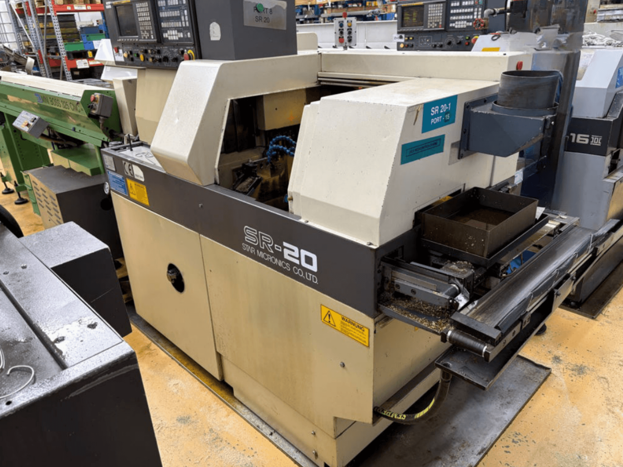 STAR MICRONICS SR20, en svarv av schweizisk typ, sedd från sidan, med kontrollpanel och verktygsområde med spån.