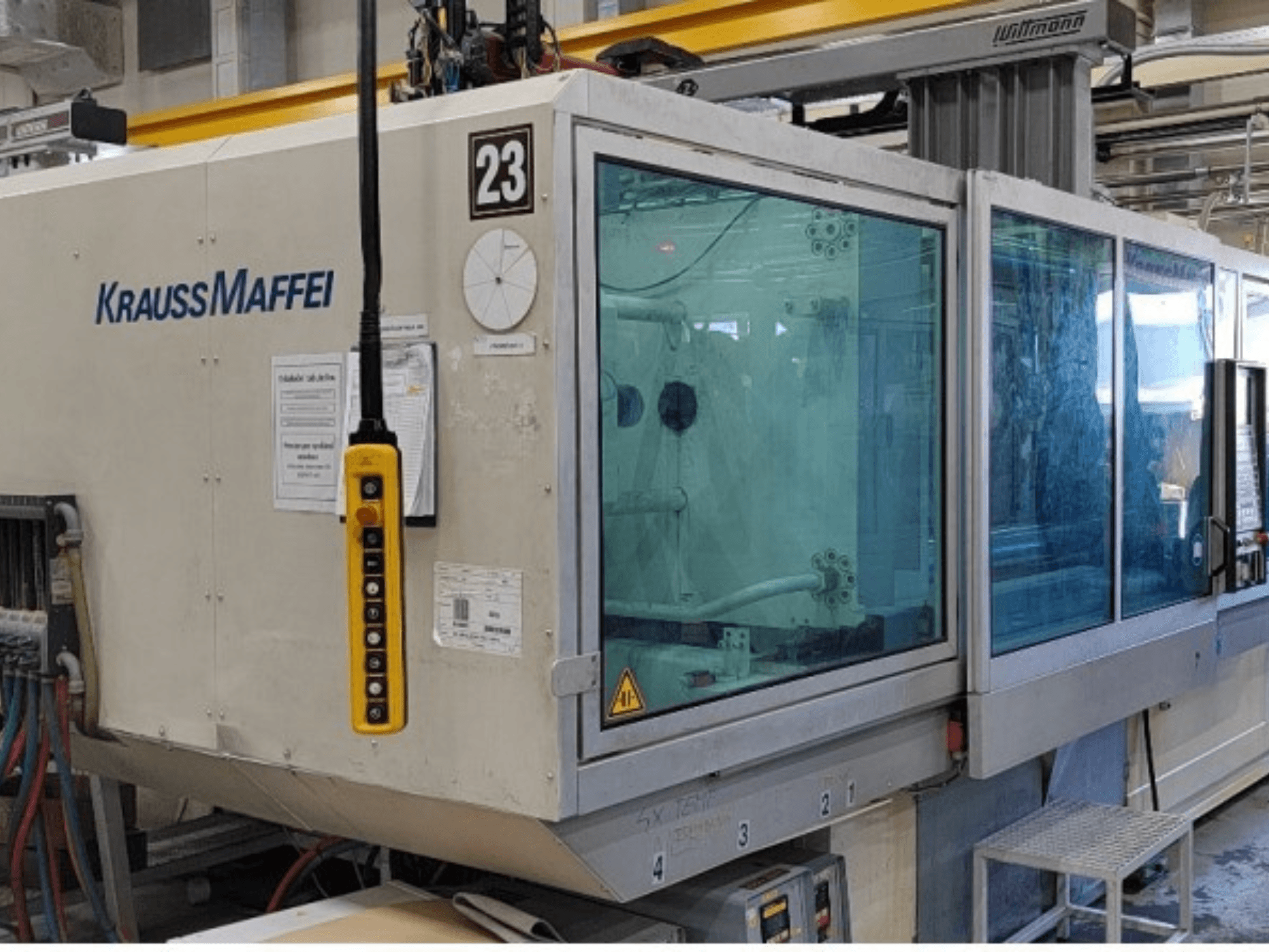 Hydraulisk formsprutningsmaskin av typen Krauss Maffei KM 350-1900 C2, framifrån sett med kontrollpanel och genomskinligt skyddshölje.