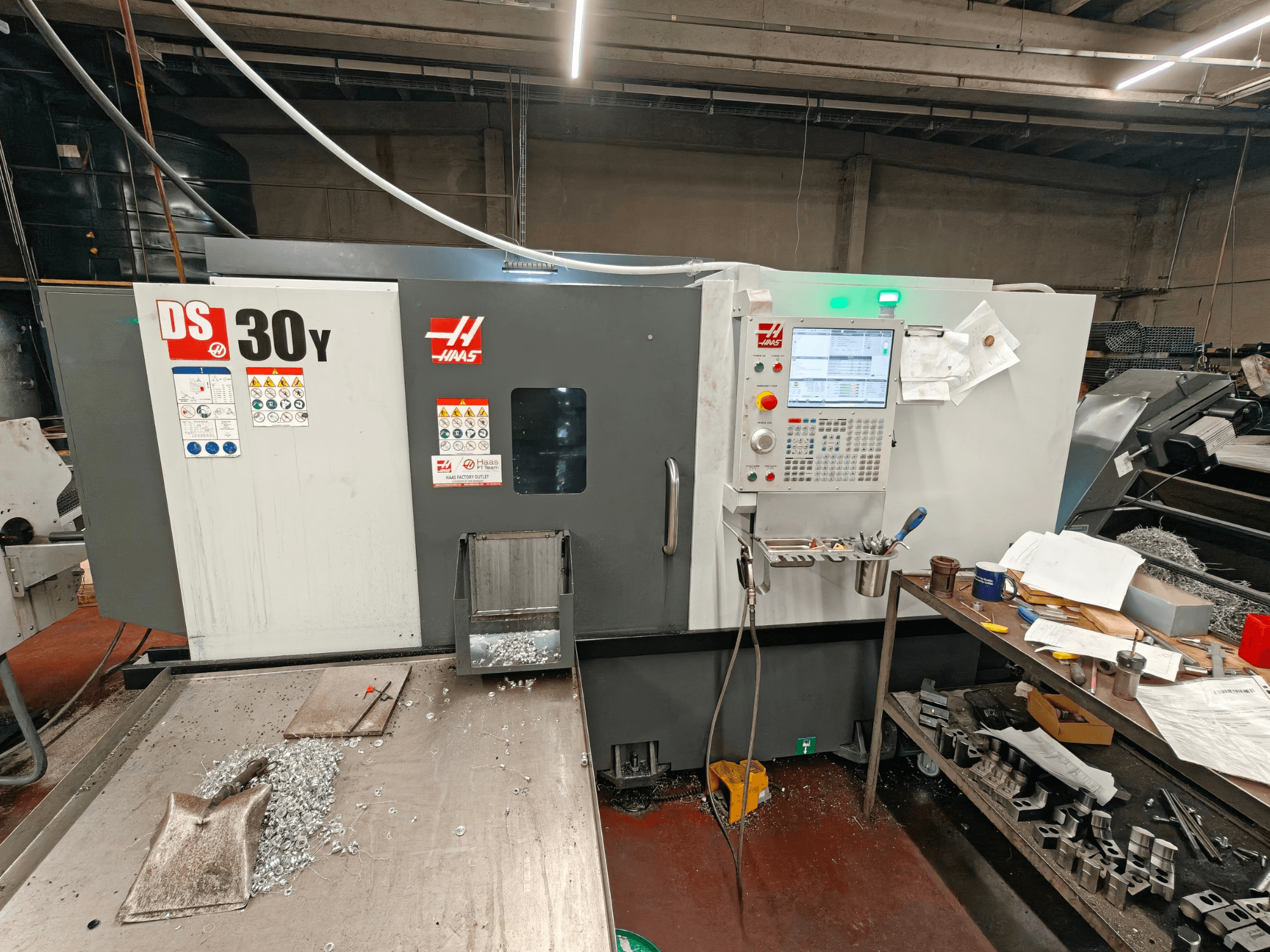 En horisontell svarv av typen HAAS DS30Y i en verkstad, framifrån sett med kontrollpanelen och metallspån på ytan.