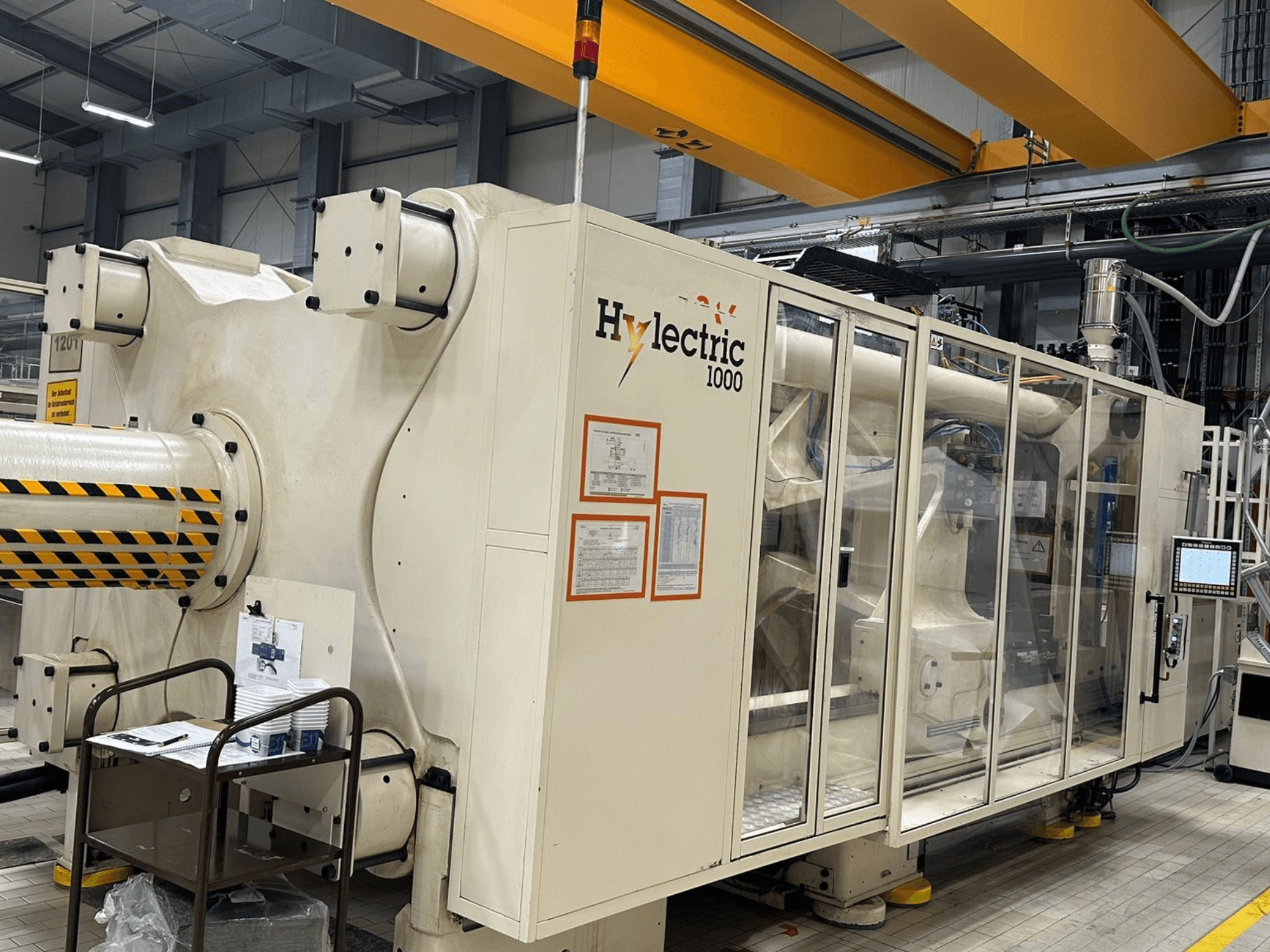 Husky Hylelectric H1000 RS95/80 – elektrisk formsprutningsmaskin, sidovy där kontrollpanelen och säkerhetsfunktionerna syns.