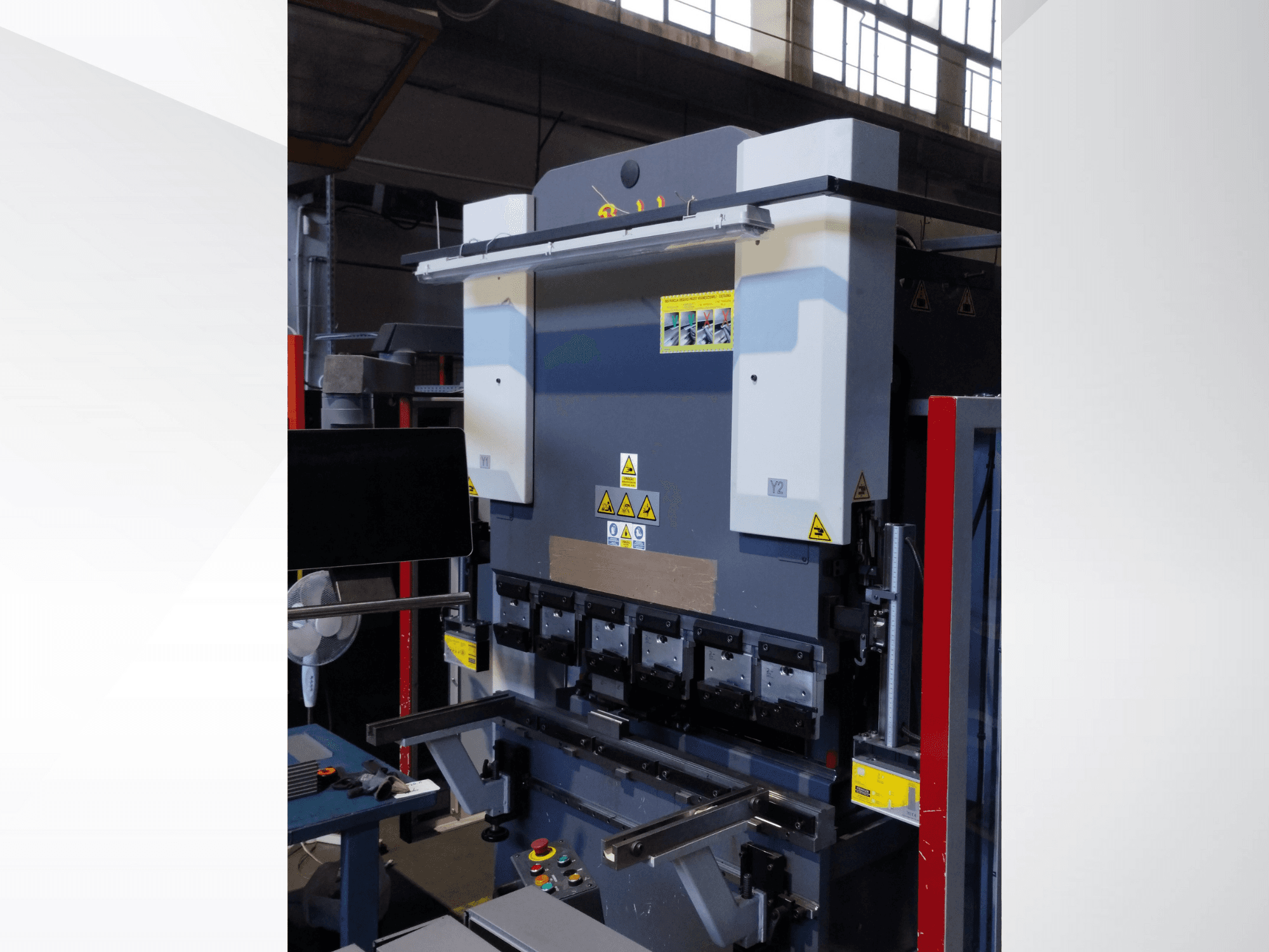 Kantpressmaskin, vy framifrån. Med synliga reglage, säkerhetsdekaler och flera verktygshållare för precisionsbockning.