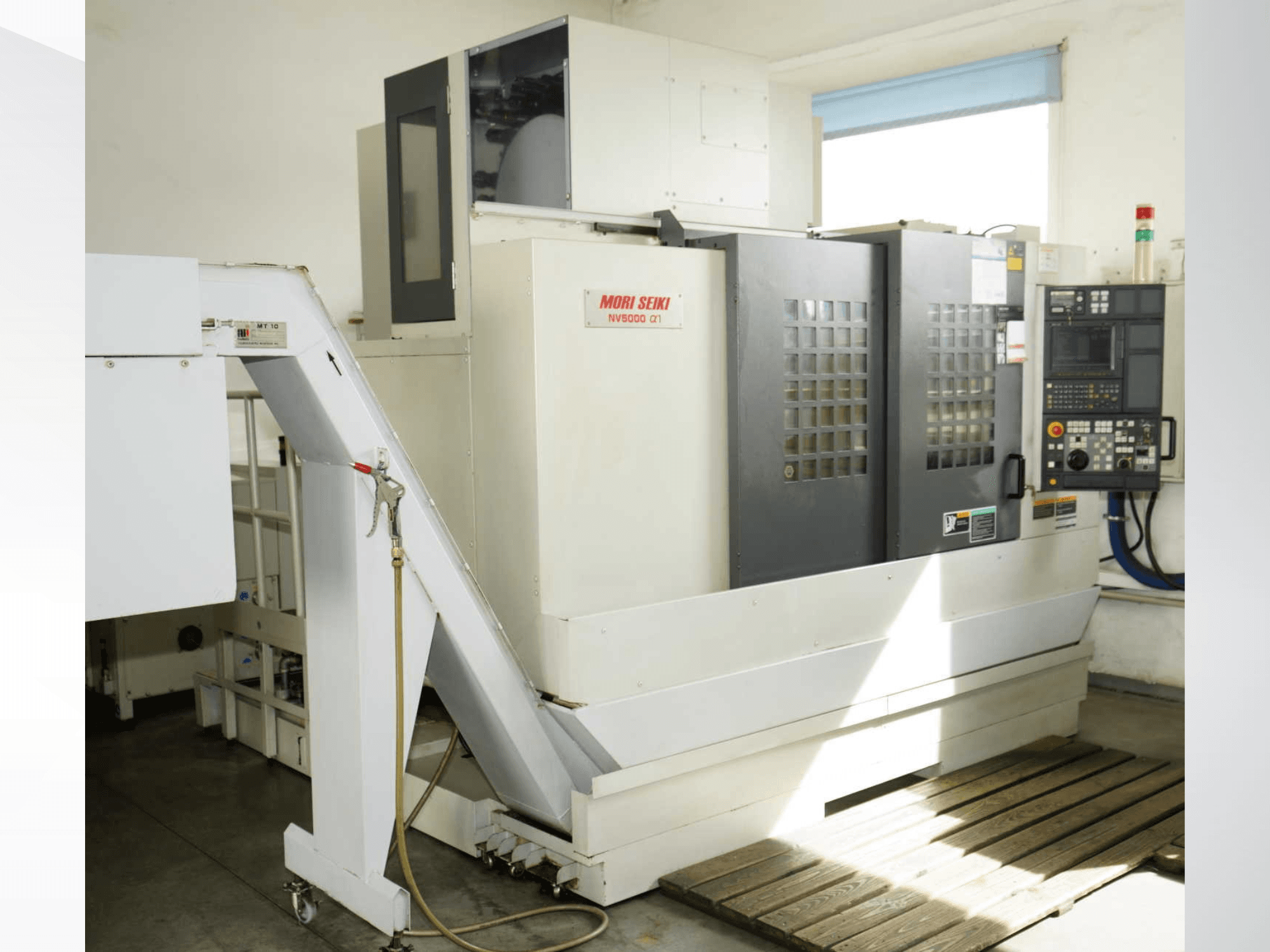 MORI SEIKI NV 5000 alpha1 vertikalt bearbetningscenter sett framifrån, med kontrollpanel, säkerhetsfunktioner och lastningsområde.