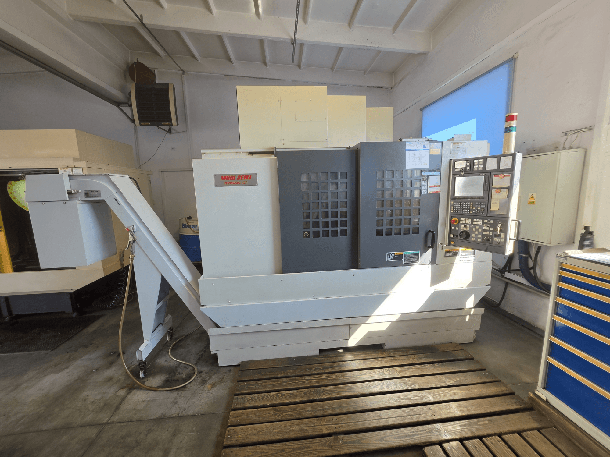 MORI SEIKI NV 5000 alpha1 vertikalt bearbetningscenter, framifrån med kontrollpanelen och maskinens funktioner i en verkstadsmiljö.
