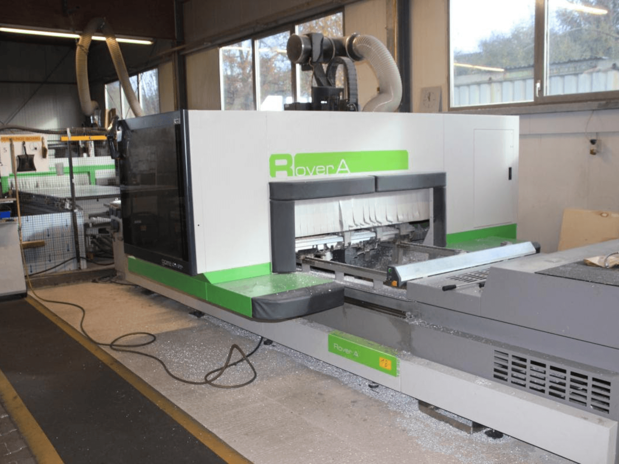 BIESSE Rover A 1232 CNC-fräs, sidovy som visar skärområdet och kontrollpanelen i en industriell miljö.