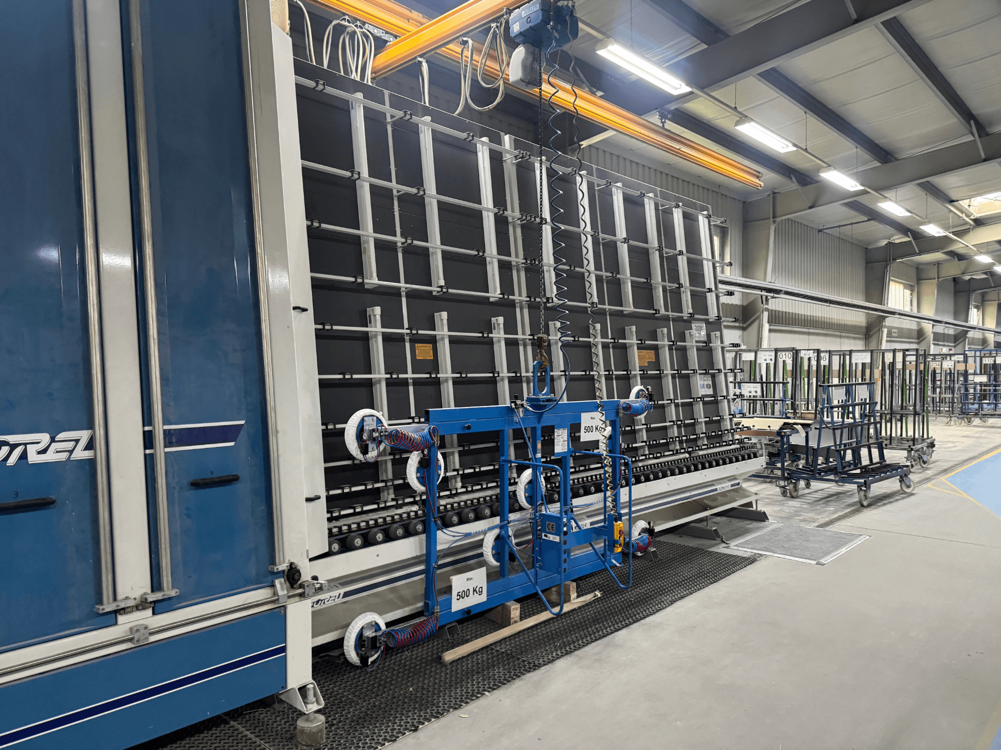 Industriutrustning från Drel, med stor ram och lyftmekanism, visad från sidan i en fabriksmiljö.