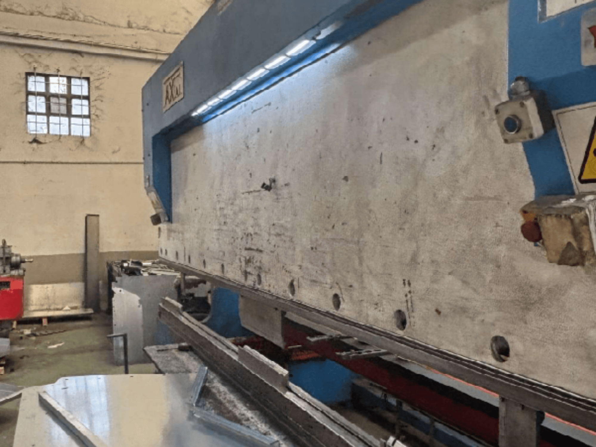 Axial PHS-W-124 pallhanteringssystem i en verkstad, sidovy som visar arbetsytan och detaljer i kontrollpanelen.