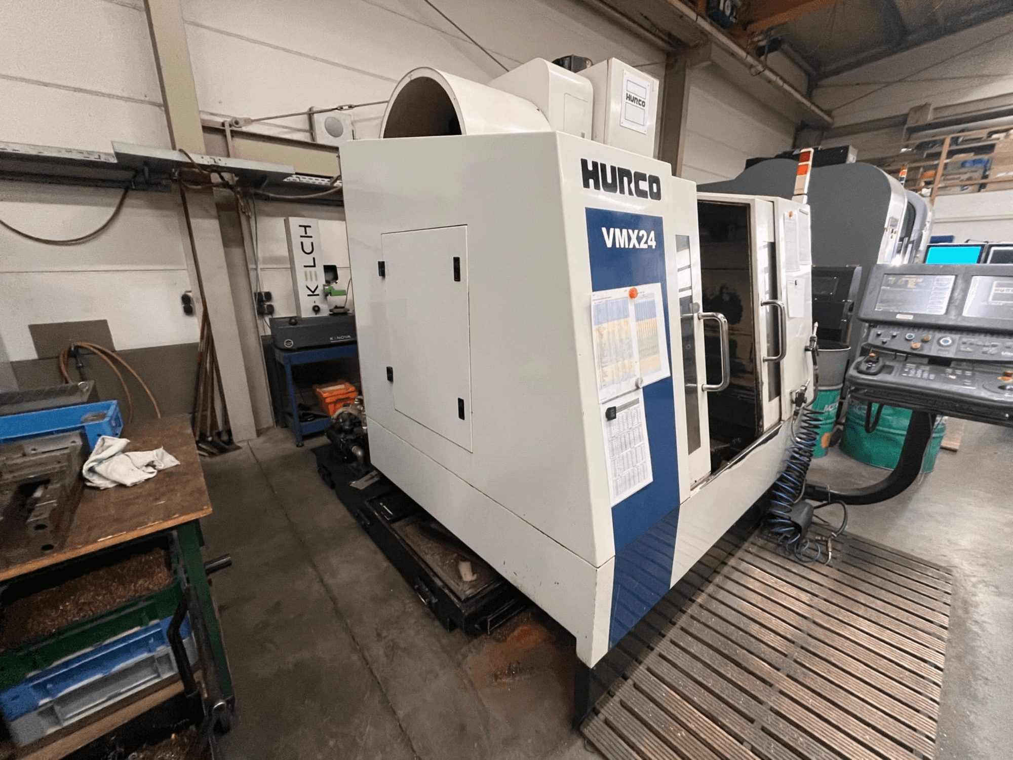 Hurco VMX24 CNC-maskin i en verkstad, vy framifrån; har en kontrollpanel och öppen åtkomstdörr.