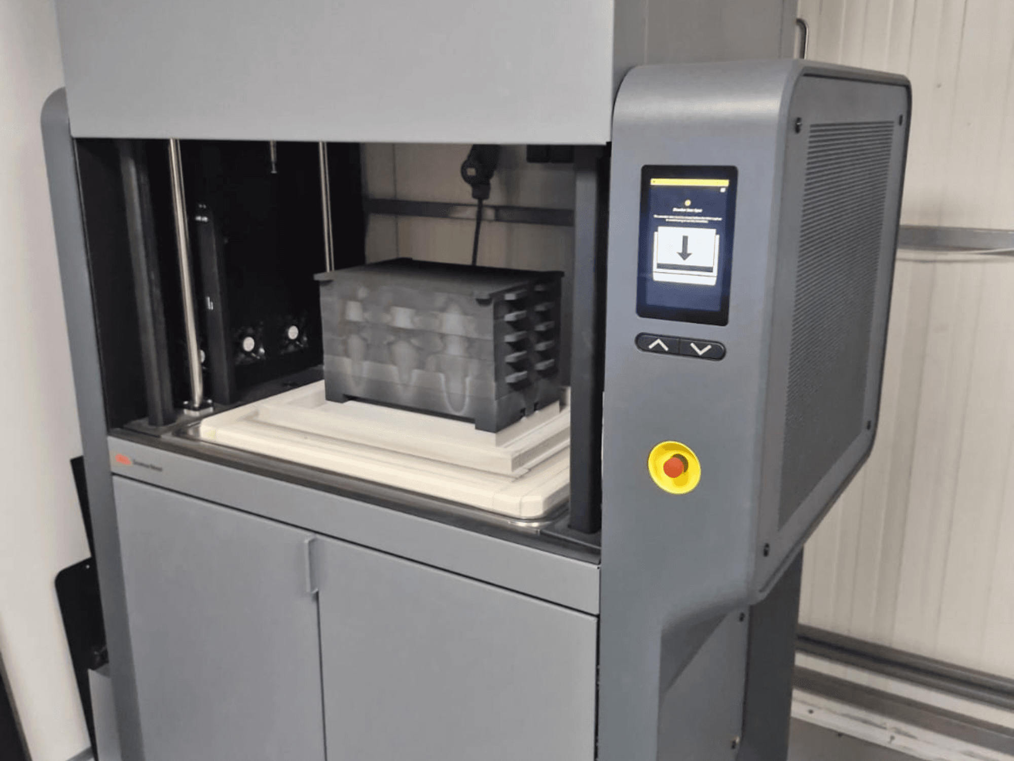 Metal Studio 2 3D-skrivare från Desktop Metal, framifrån med kontrollpanel och skrivbädd med svart behållare.