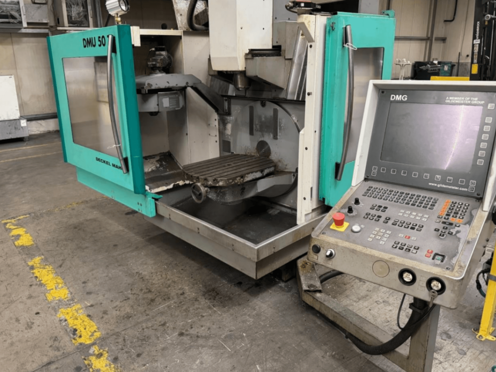 DMG DMU 50 fräsmaskin med öppna dörrar som visar interiören och kontrollpanelen, sedd framifrån.