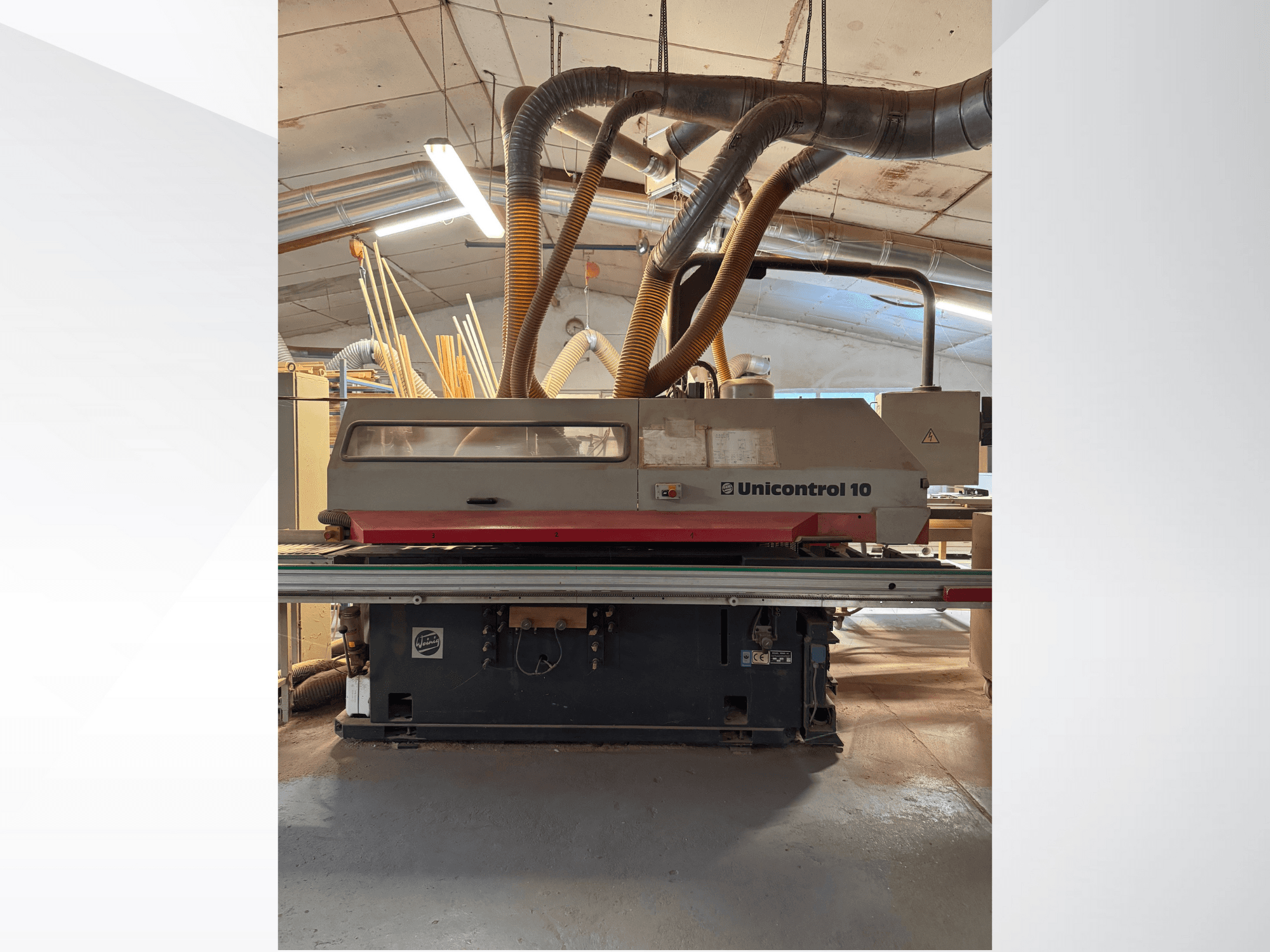 Frontvy av en Unicontrol 10 träbearbetningsmaskin, med dammutsugningsrör och manöverreglage.