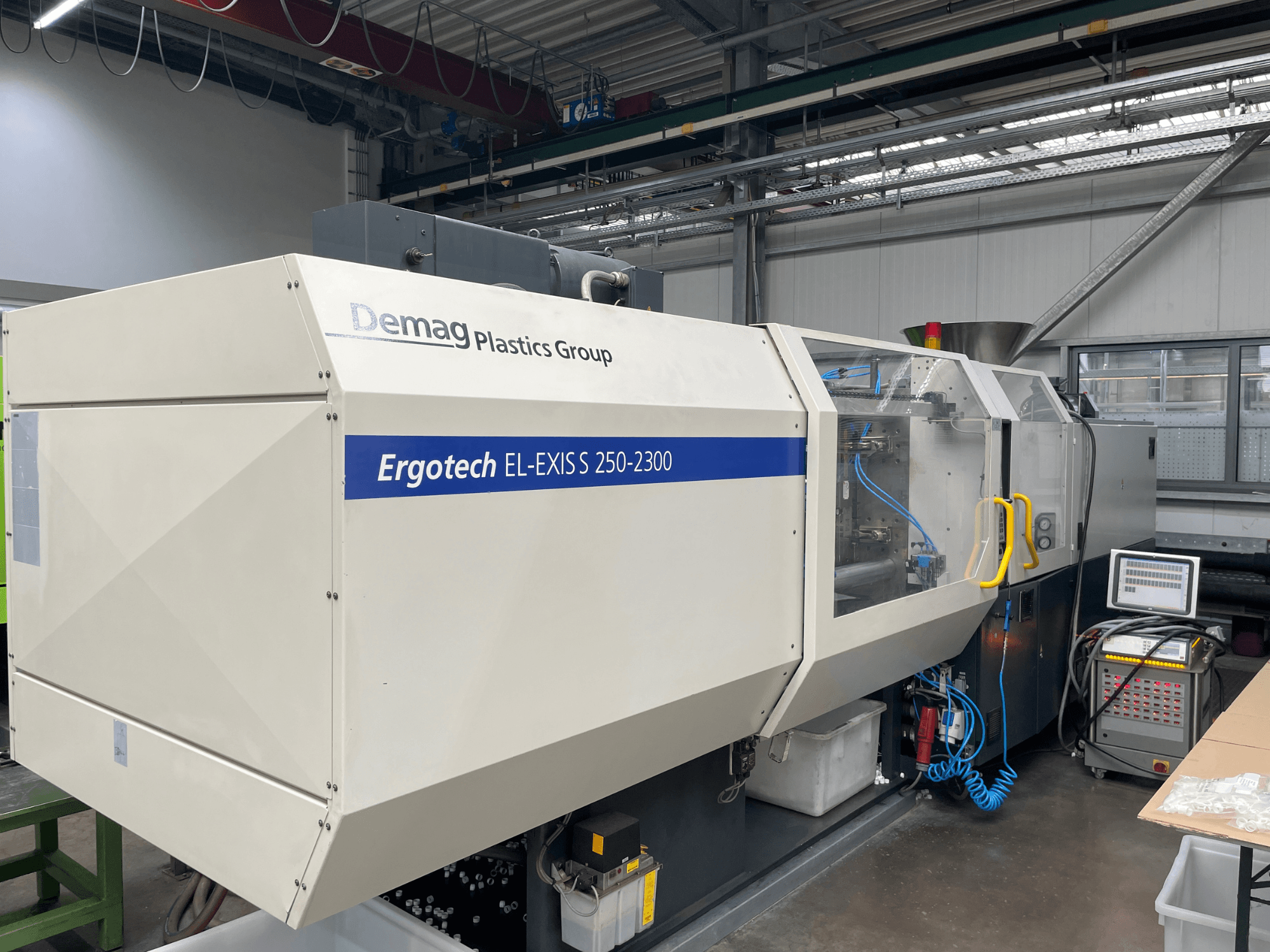 Demag Ergotech EL-EXIS S 250-2300 formsprutningsmaskin, sidovy, visar kontrollpanel och matningssystem.