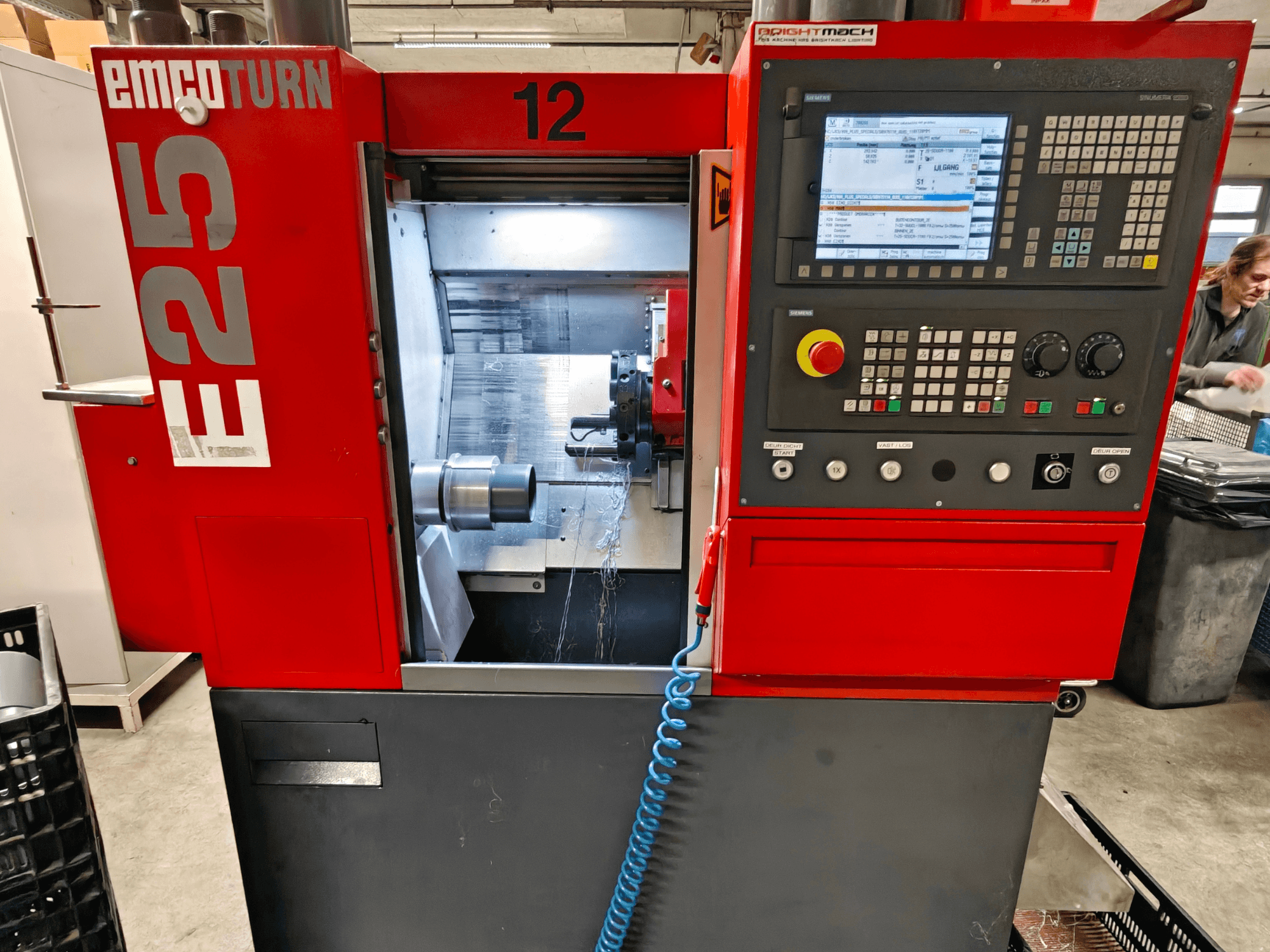 EMCO TURN E25-maskinens framsida, med kontrollpanel, verktygshållare och inre område med skärverktyget synligt.