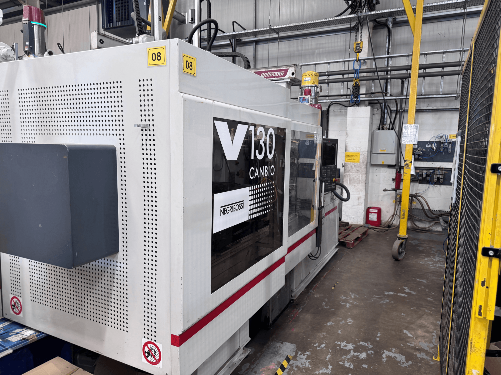 Hydraulisk formsprutningsmaskin av typen Negri Bossi 1300H-400, sidovy, med kontrollpanel och säkerhetsskyltar.