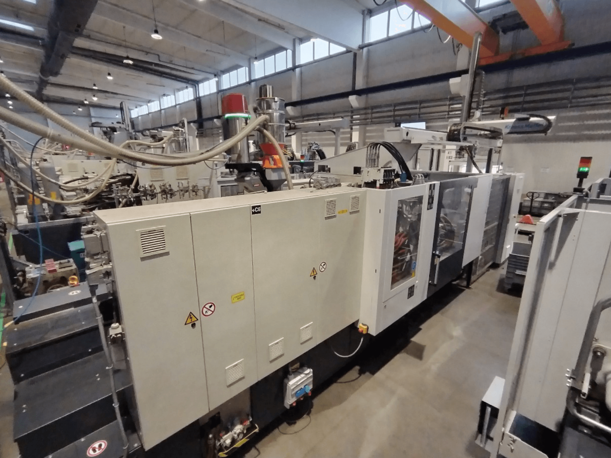 Industriell formsprutningsmaskin sedd från sidan, med kontrollpanel och säkerhetsvarningar. Varumärke: Okänt.