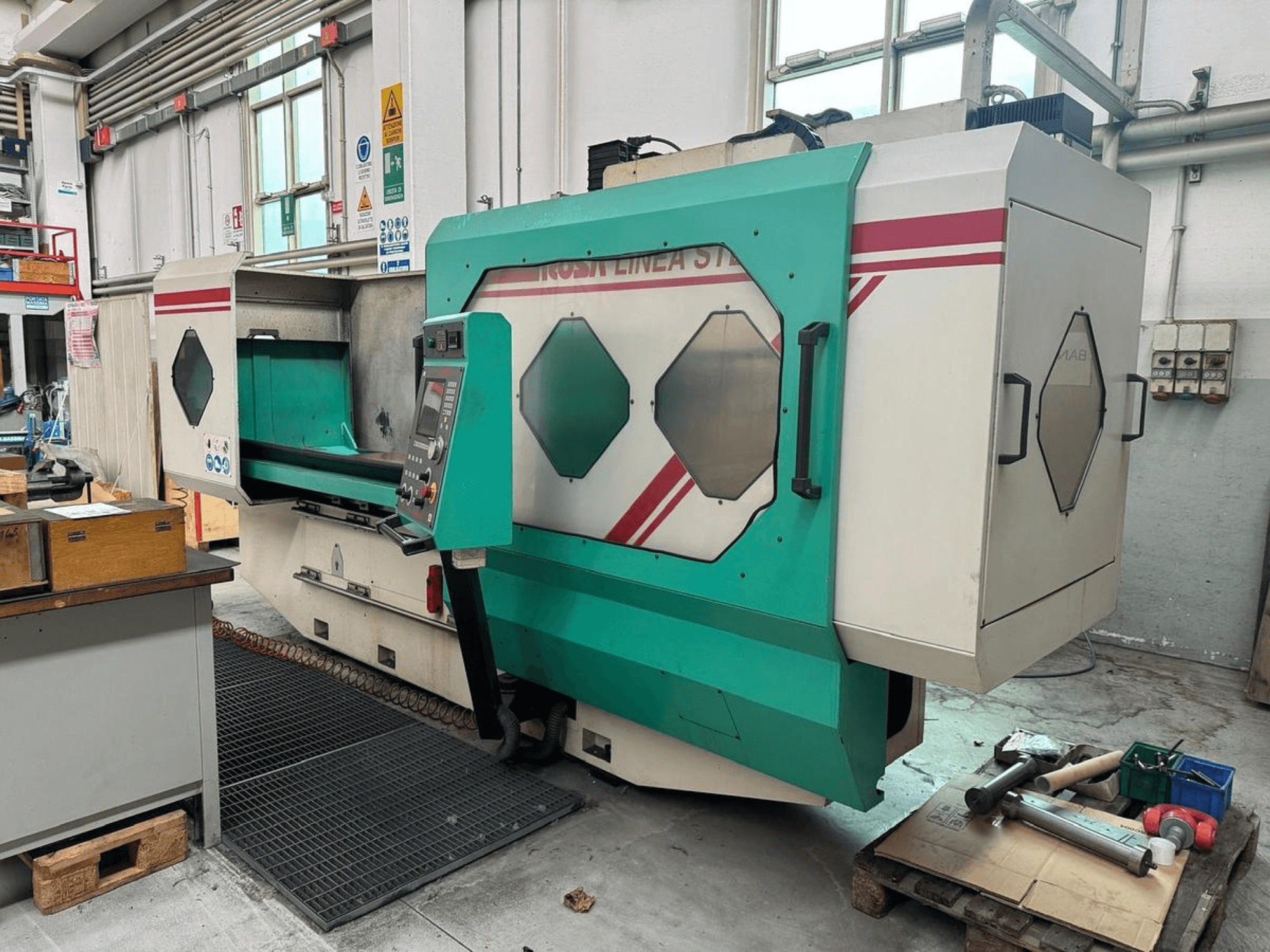 Grönvit precisionsmaskin, framifrån, med kontrollpanel, arbetsområde och verktyg på en pall. Varumärke: BAMB.