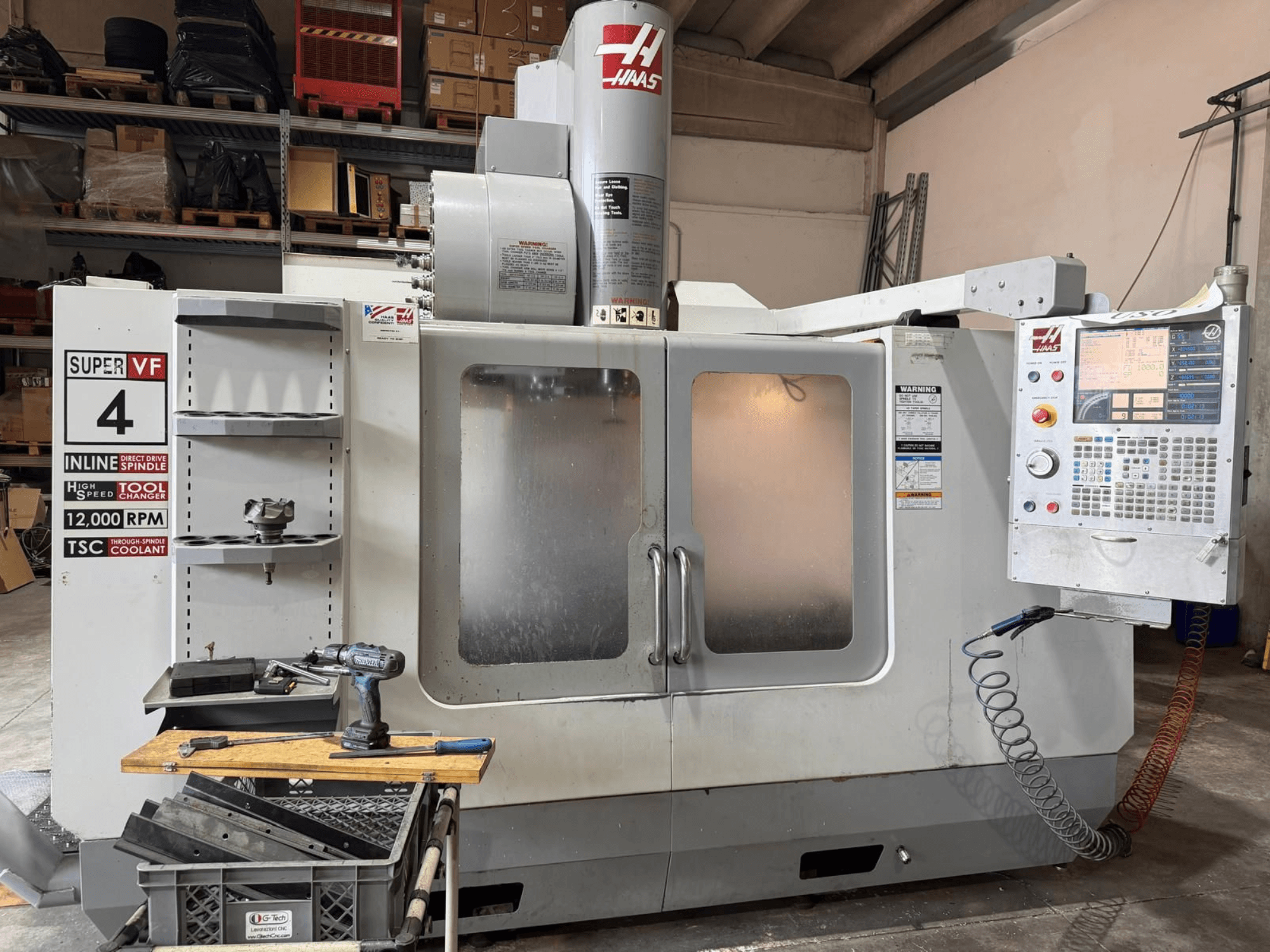 Framifrån sett på det vertikala bearbetningscentret HAAS VF-4SSHE med manöverpanel, verktygsställ och spindel med 12 000 varv per minut; en höghastighetsmaskin med hög precision.