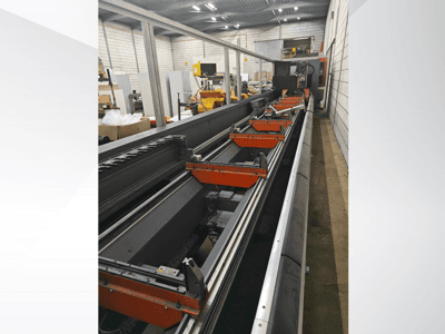 Industriell CNC-maskin i sidovy med linjära skenor, orangefärgade klämmor och precisionskomponenter i en lagerlokal.