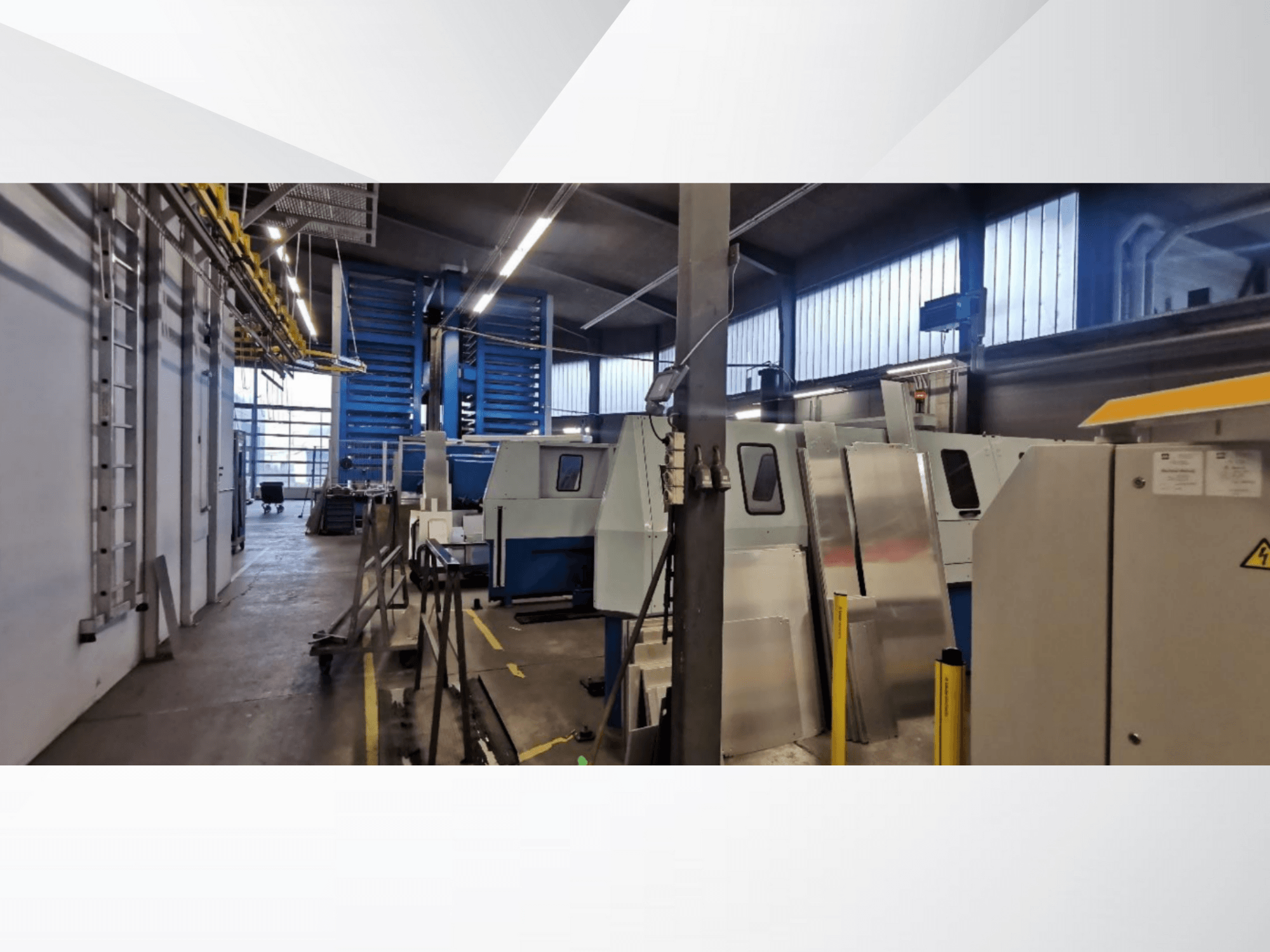 Industriell verkstadsscen med flera maskiner och utrustning i sidovy, med metallytor och synliga säkerhetsanordningar.