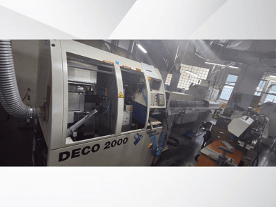 DECO 2000 CNC-maskin i en verkstad, vy framifrån, med reglage och en uppställning för långa arbetsstycken till höger.