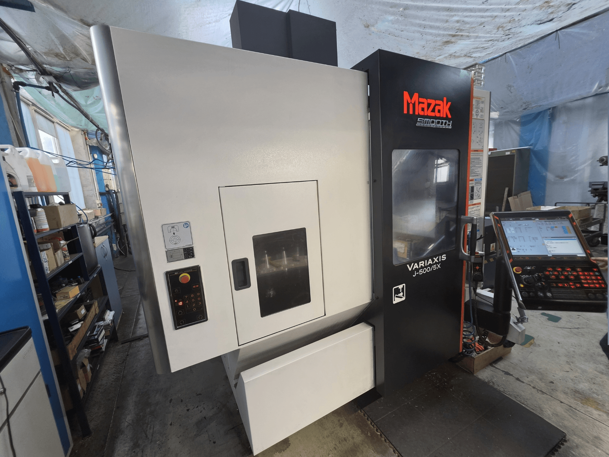 Mazak VARIAXIS J-500/5X vertikalt bearbetningscenter sett framifrån, med en kontrollpanel och ett stort fönster mot bearbetningsområdet.
