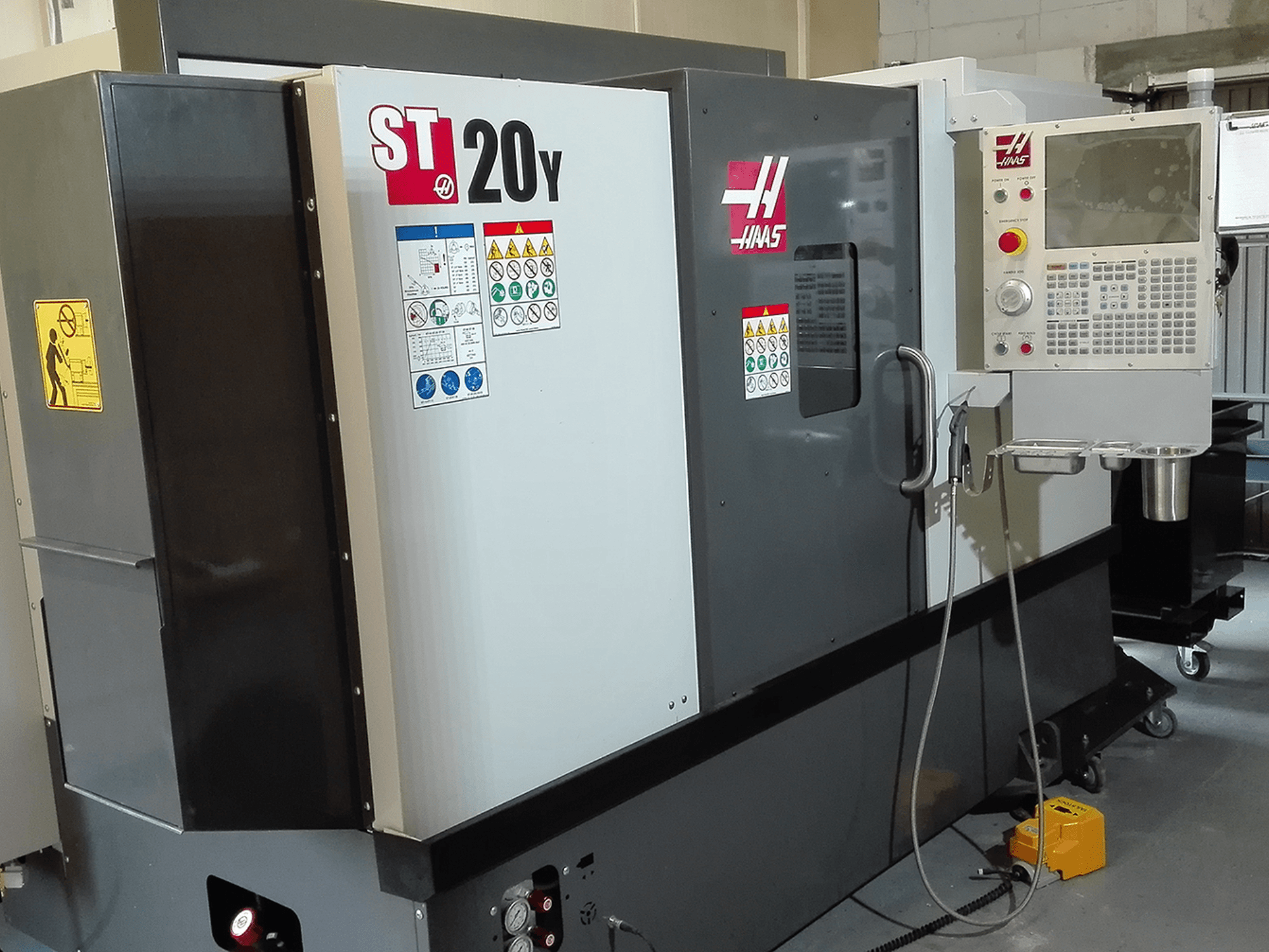 Haas ST20Y CNC-svarv framifrån, med manöverpanel, säkerhetsetiketter och kylvätskesystem.