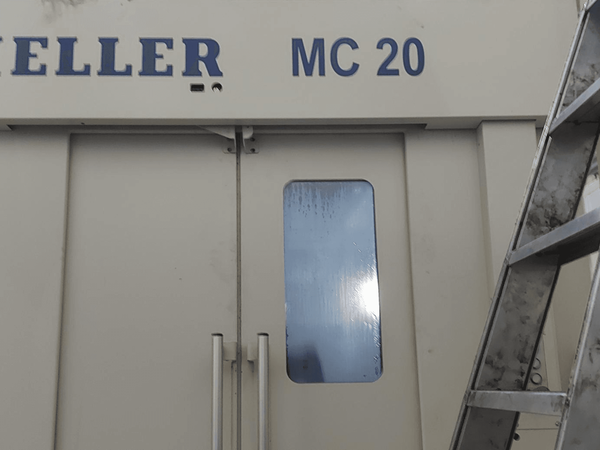 HELLER MC 20 horisontell fleroperationsmaskin framifrån, med dörrhandtag och ett litet fönster. Stege på sidan.