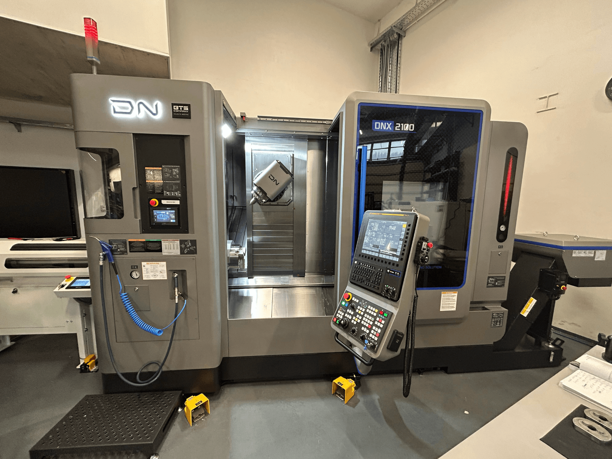 DN ONX 2100 CNC-maskin, vy framifrån, med kontrollpanel, arbetsområde och verktyg. Utrustad med säkerhetslampa och driftindikatorer.