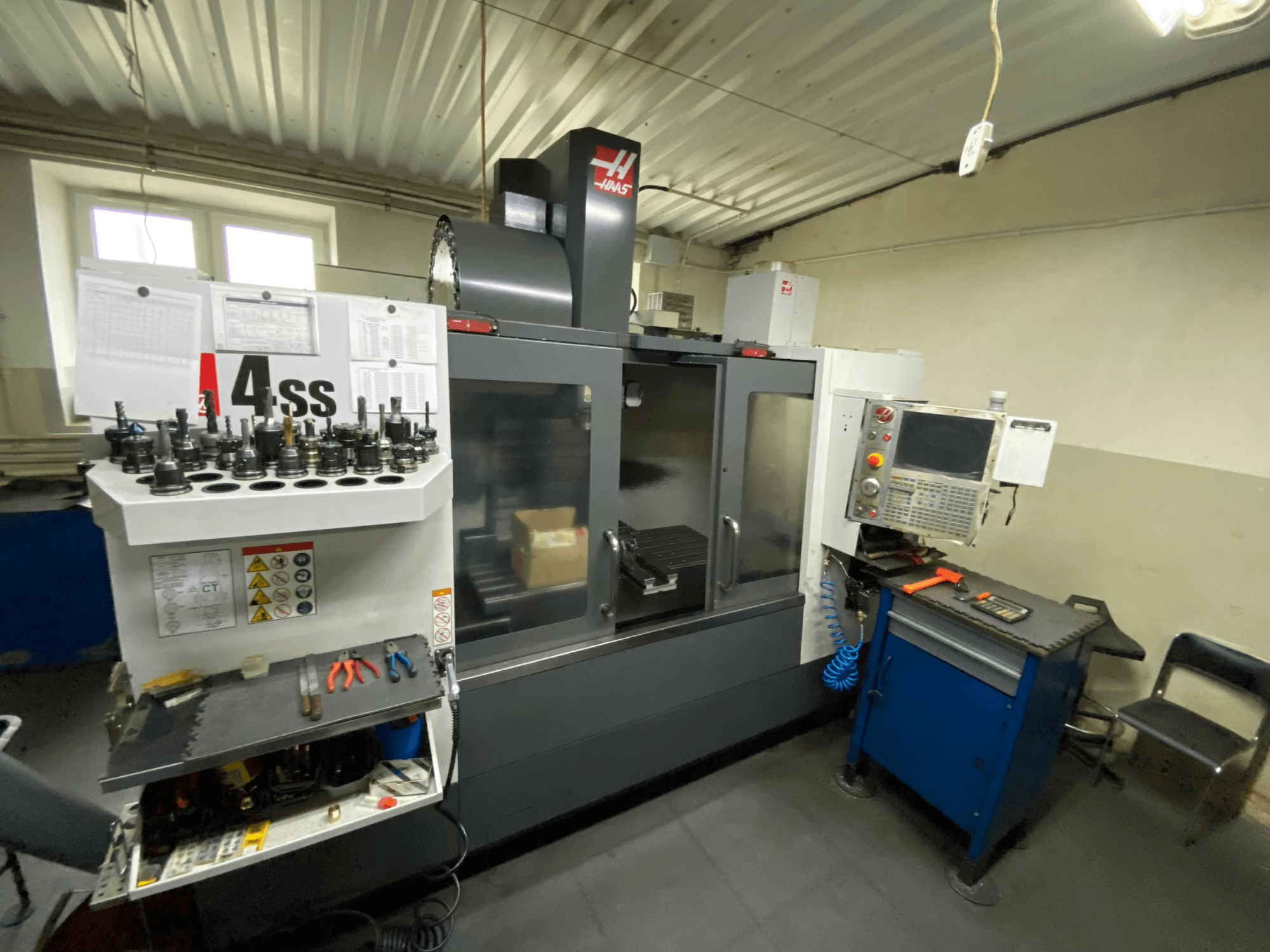Haas VF-4SS vertikalt bearbetningscenter, framifrån med verktygshållare och manöverpanel. Verktyg och arbetsområde syns tydligt.