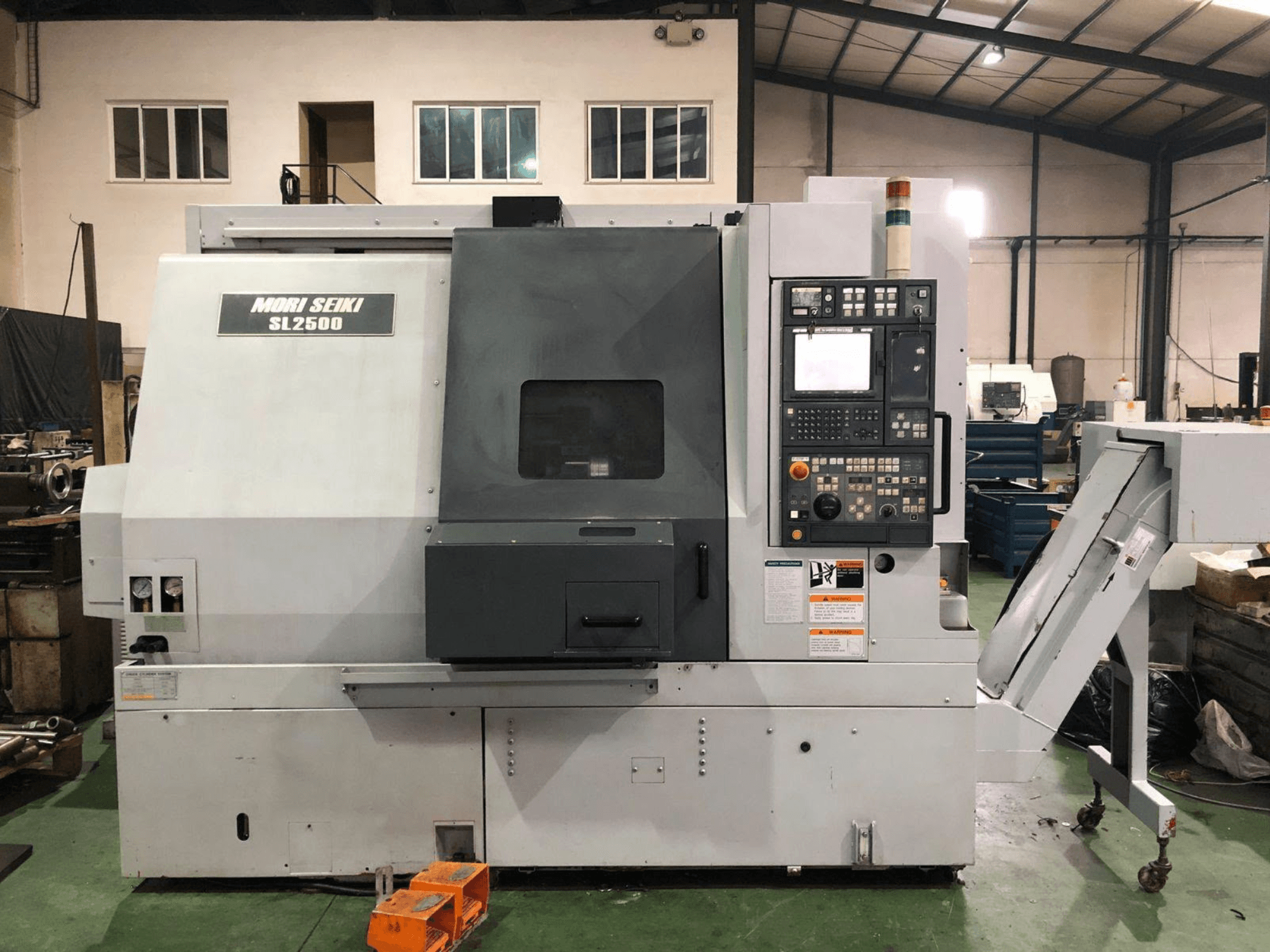 DMG Mori Seiki SL 2500 Y-varv- och fräscenter, sidovy där kontrollpanelen och spåntransportören syns.