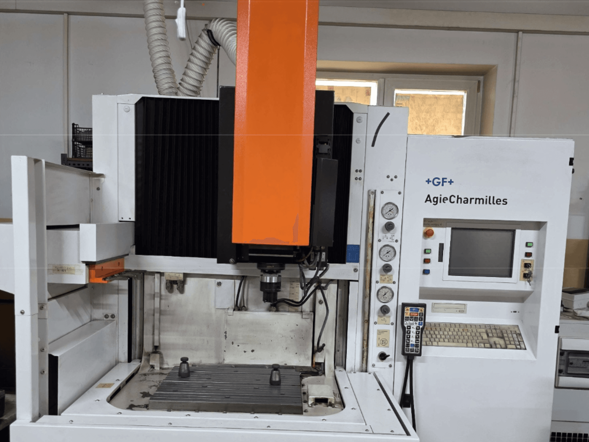 AgieCharmilles bearbetningscenter framifrån med en stor orange spindel, kontrollpanel och synligt arbetsbord.