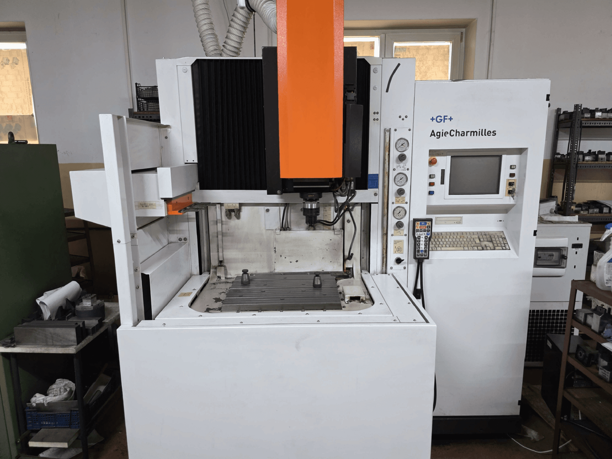 GF AgieCharmilles CNC-maskin, framifrån med en framträdande orange spindel, digital kontrollpanel och monterat borrbord.
