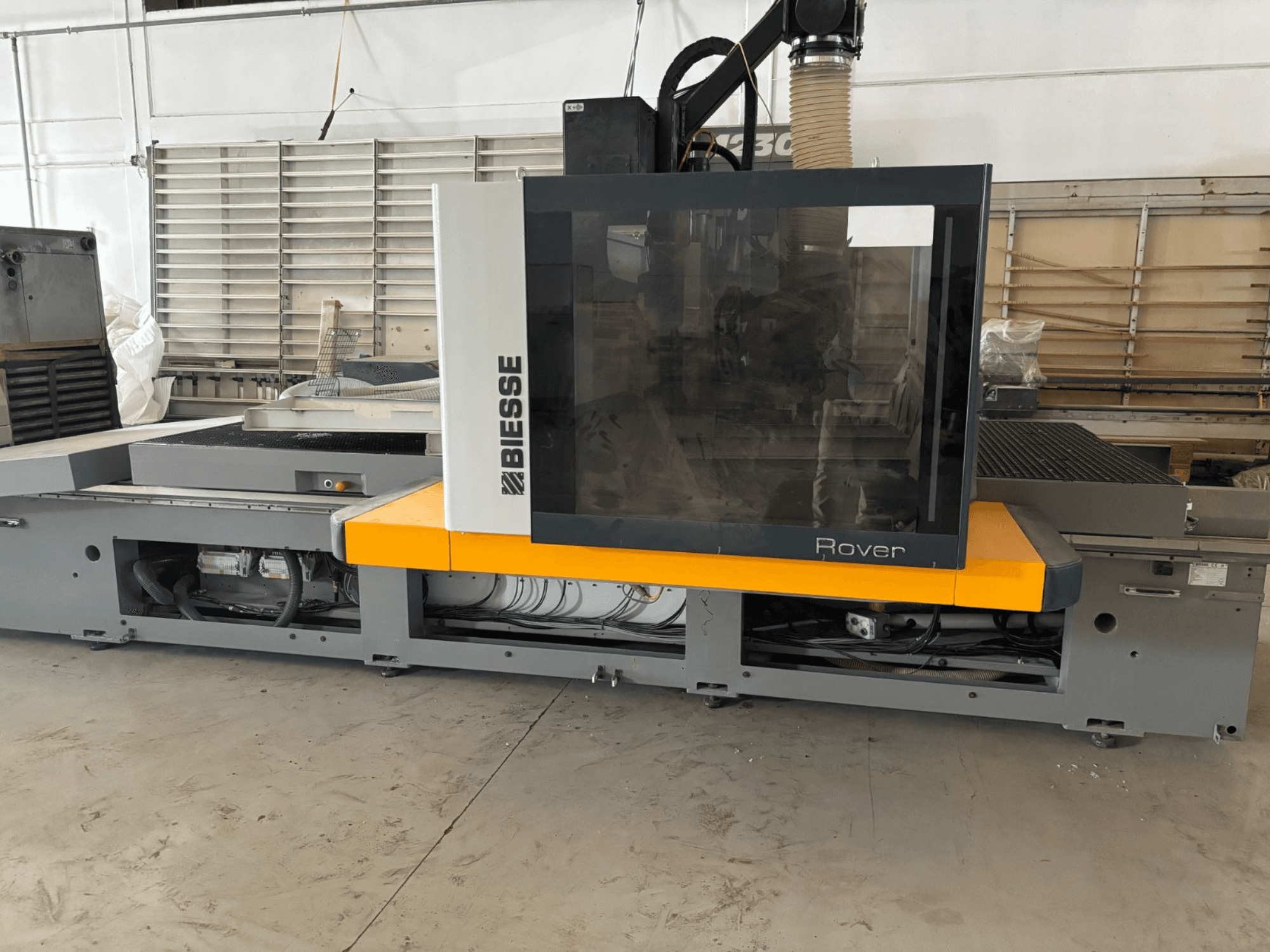 Biesse Rover CNC-bearbetningscenter, framifrån, har en stor kontrollpanel, gula accenter och synliga mekaniska komponenter.