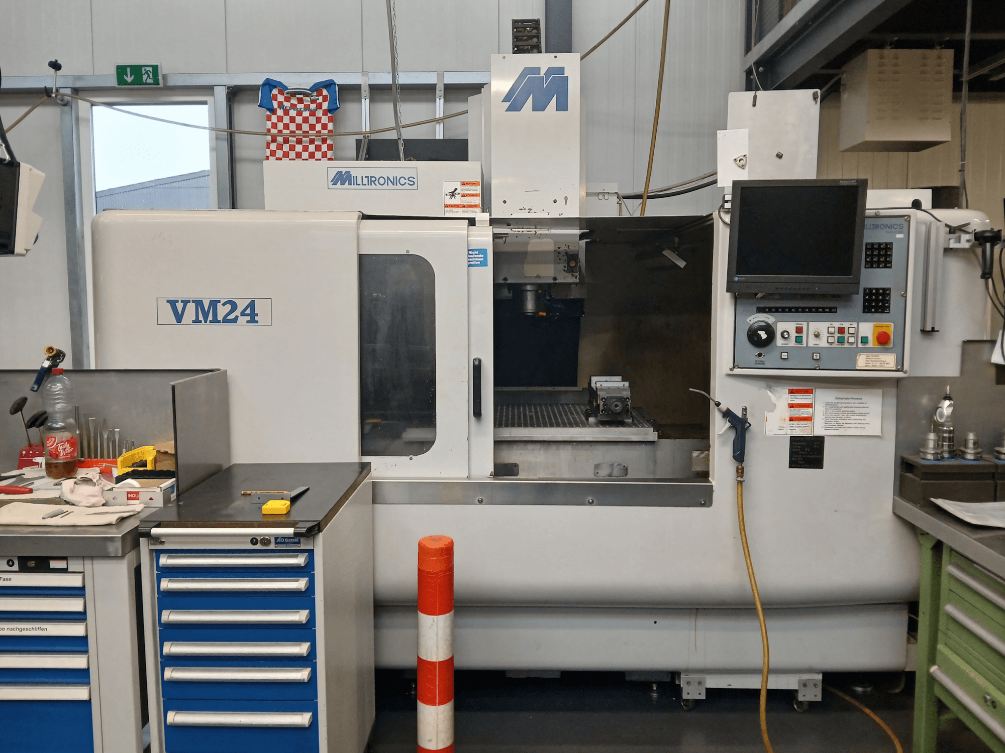 Milltronics VM24 CNC-fräsmaskin visad framifrån, med kontrollpanel, verktygsförvaring och arbetsområde.