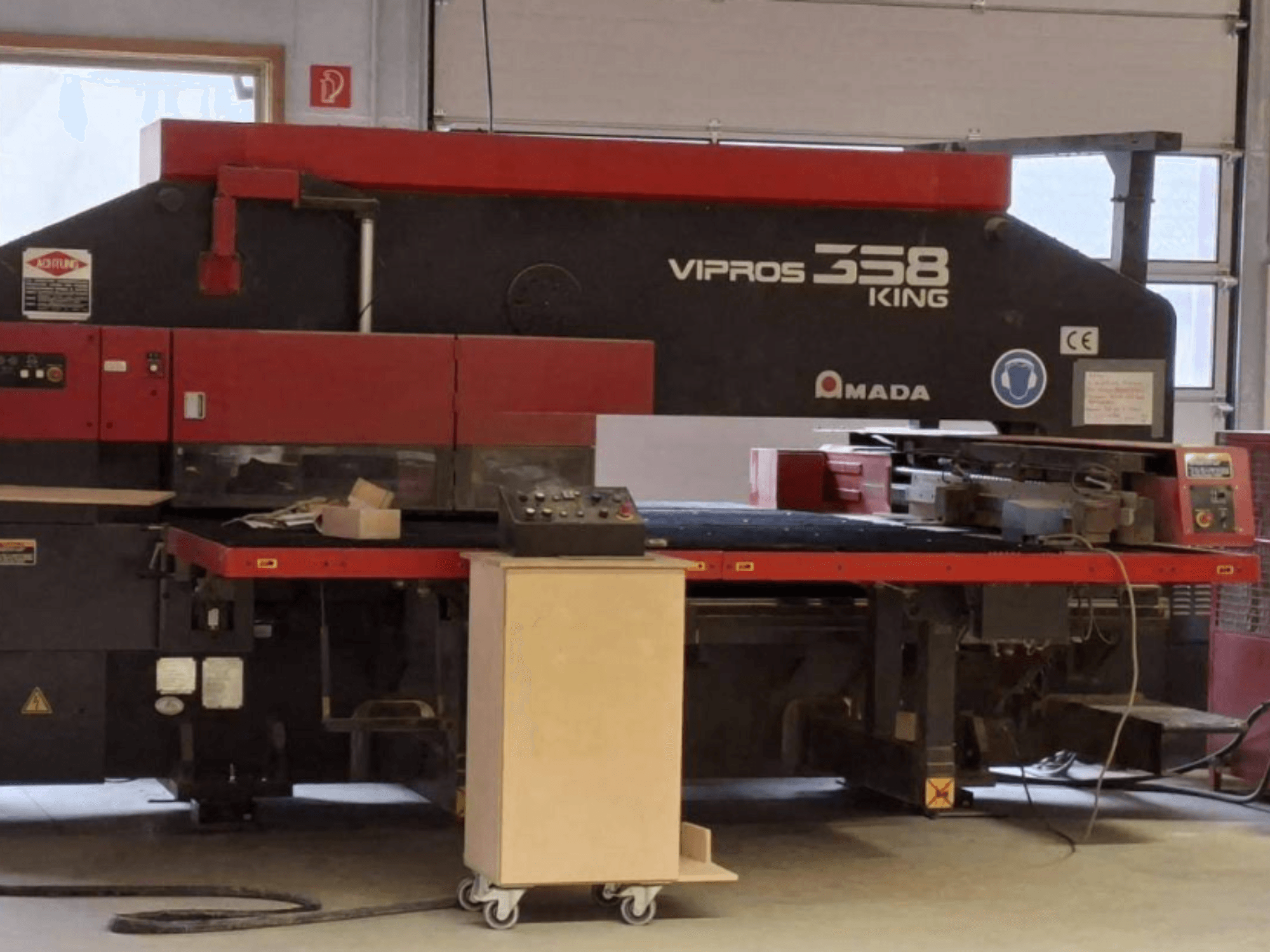 CNC-stansmaskin AMADA VIPROS 358 KING i sidovy, med kontrollpanel och verktygsförvaringsutrymme.