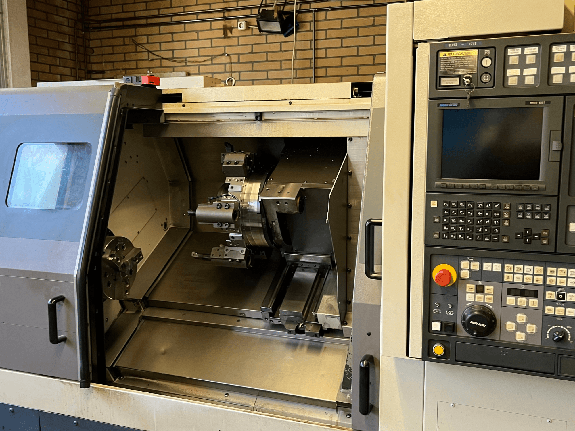 MORI SEIKI SL-253B MC/1000 horisontell svarv, frontvy som visar kontrollpanel och öppen kammare med bearbetade detaljer.