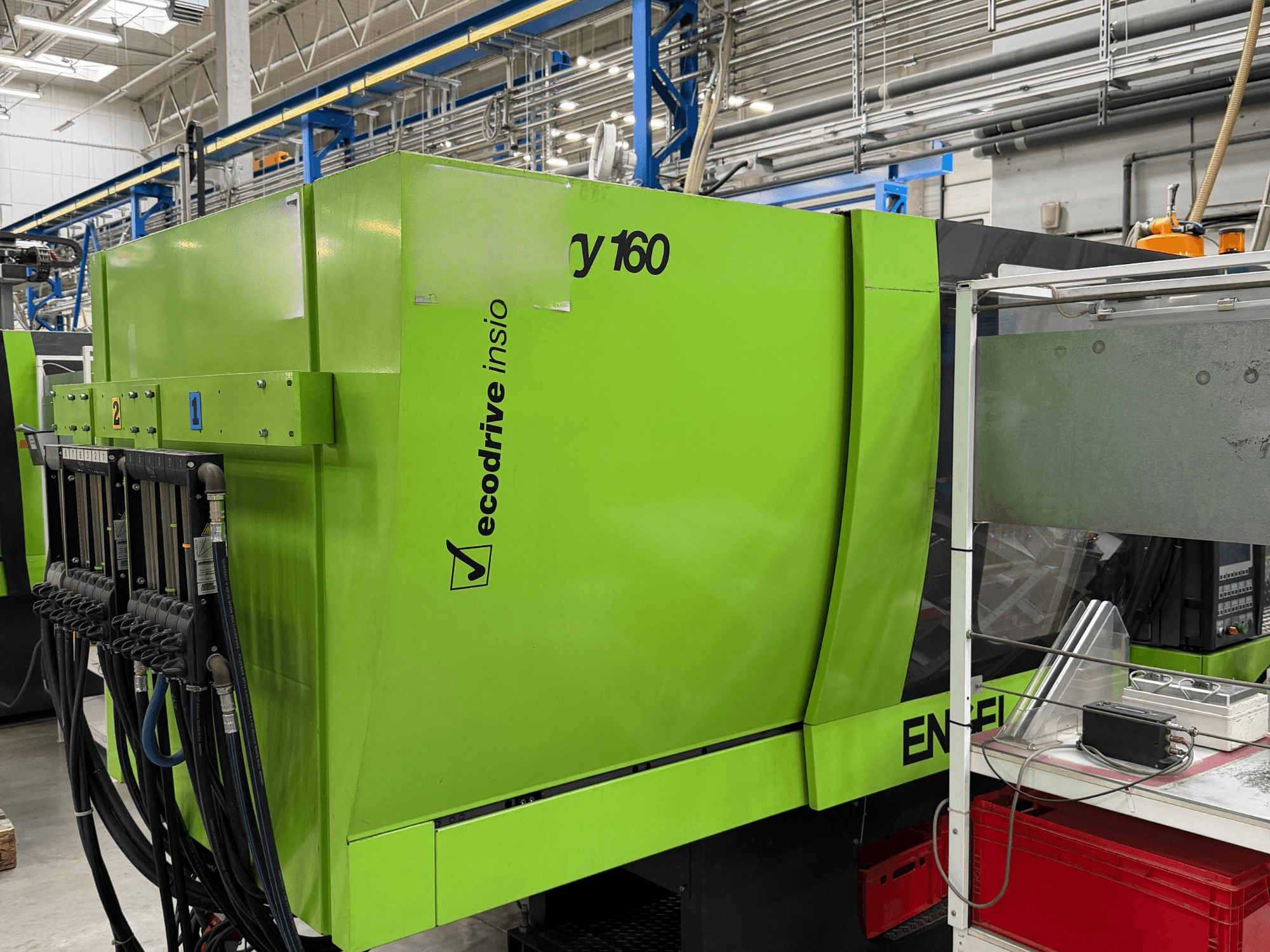 Hydraulisk formsprutningsmaskin av typen Engel Victory 500/160 tech i grönt, sidovy som visar kontrollpanelen och Ecodrive-funktionen.