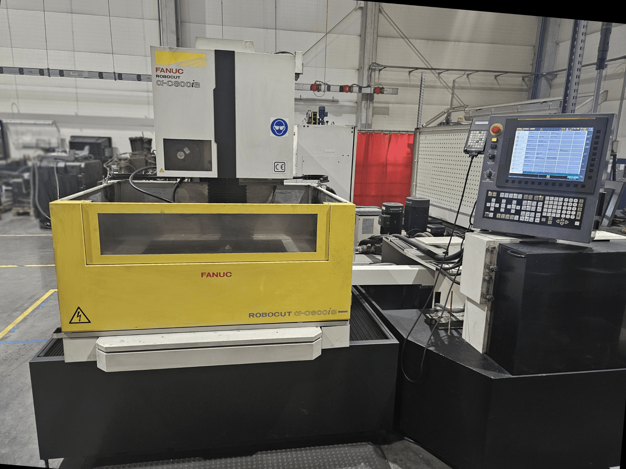 Frontvy av FANUC Robocut α-C600iB med gul och grå maskinkropp, CNC-kontrollpanel och driftdisplay.