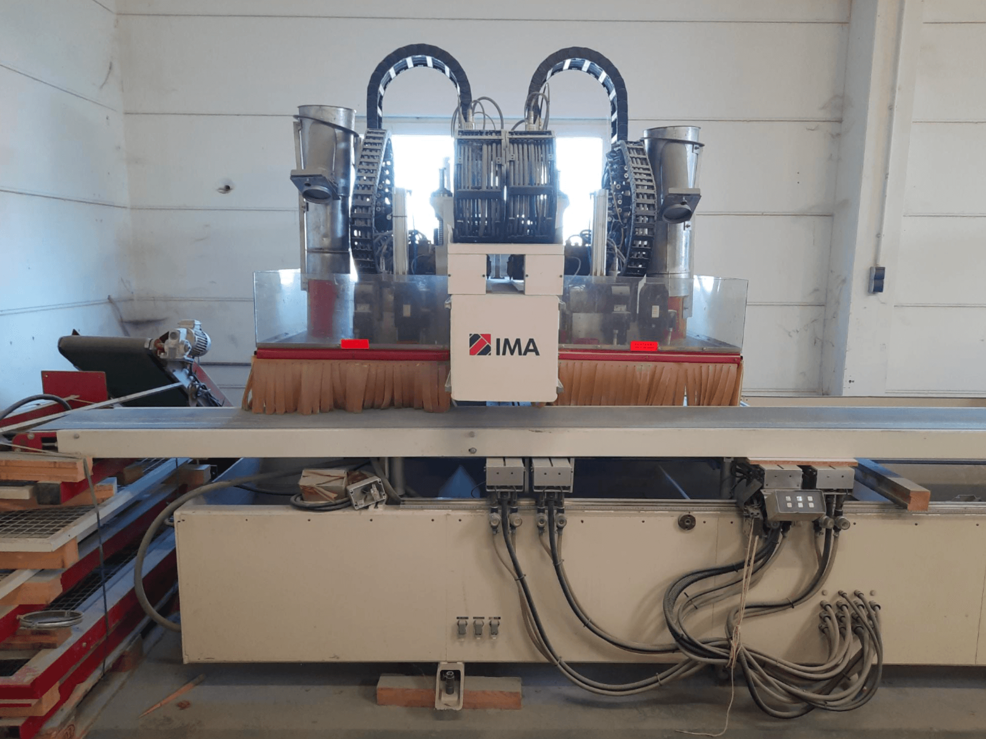CNC-bearbetningscenter för trä IMA BIMA 610 V sett framifrån, med borstar, manöverpaneler och ett arbetsbord.