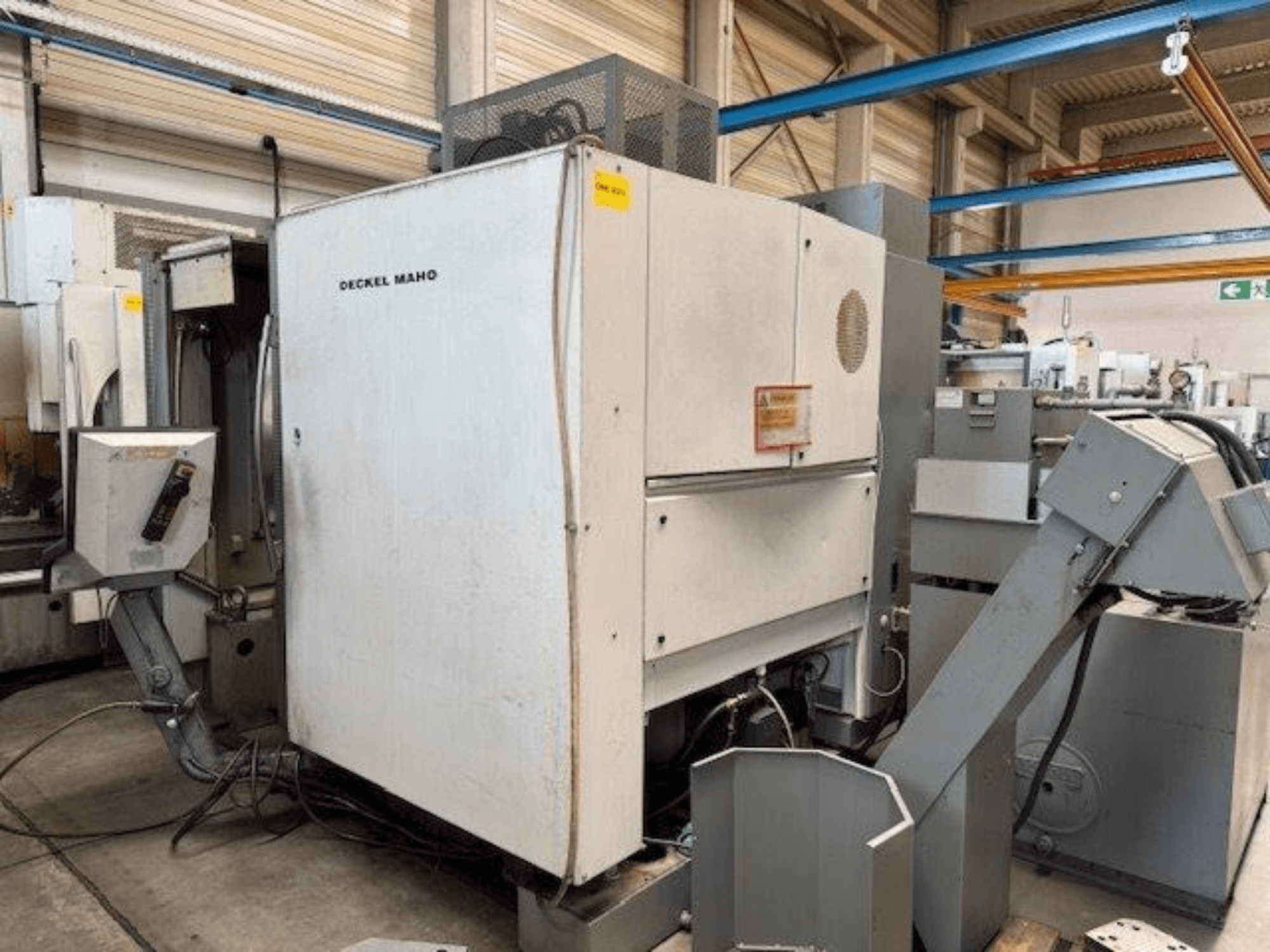 DECKEL MAHO DMC 100 V vertikal fleroperationsmaskin, sidovy med kontrollpanel och olika tillbehör synliga.