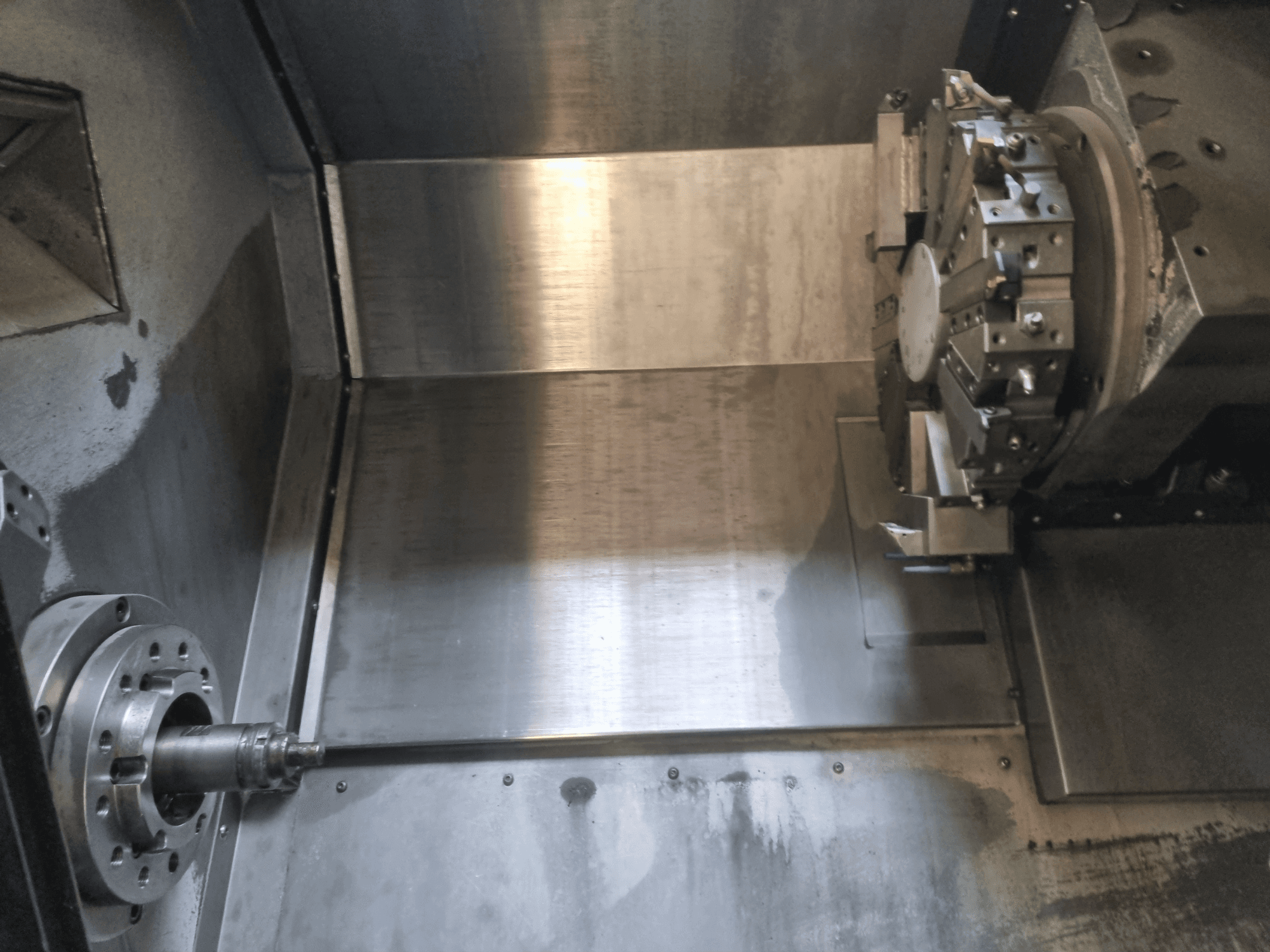 Invändig vy av en CNC-svarv med roterande spindel och arbetsyta i metall, som visar industriell precisionsteknik.