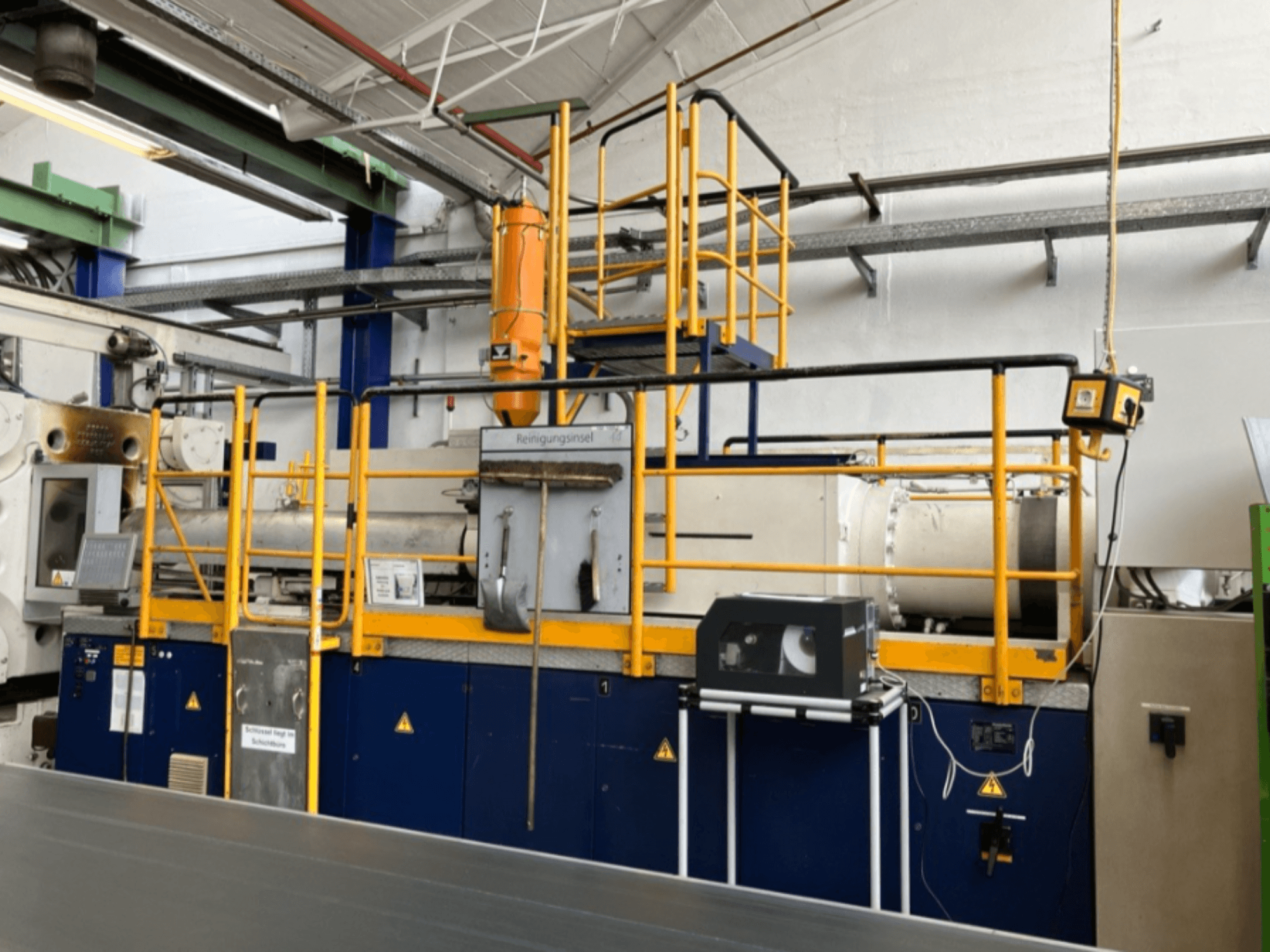 Krauss Maffei 1000-8000 M hydraulisk formsprutningsmaskin, sidovy med säkerhetsräcke och kontrollpanel synlig.