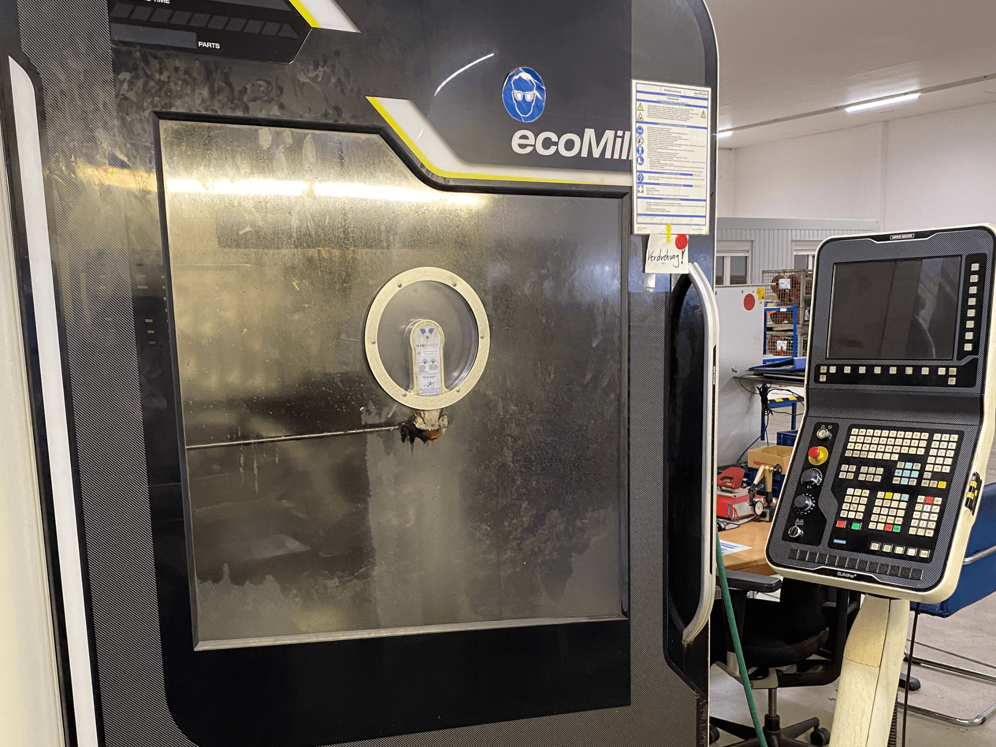 DMG MU 70 ECO-fräs sett framifrån, med en kontrollpanel till höger och en glasruta som ger insyn i de inre komponenterna.