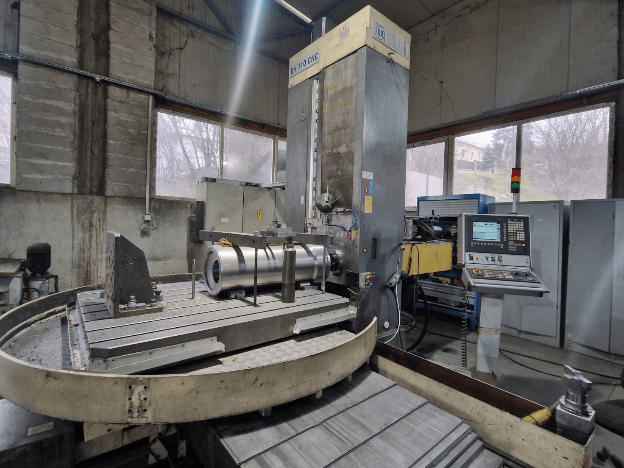 LOLA BH 110 CNC-borrmaskin i en verkstad, framifrån, med arbetsstycke i metall och kontrollpanel.