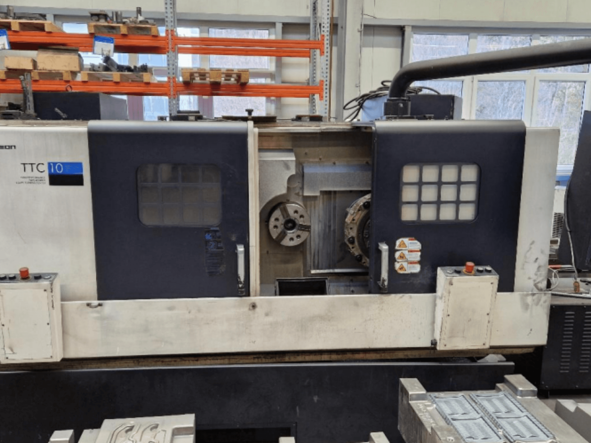 TTC 10 svarvmaskin framifrån, med kontrollpanel, synliga chuckar och arbetsyta med metalldelar.