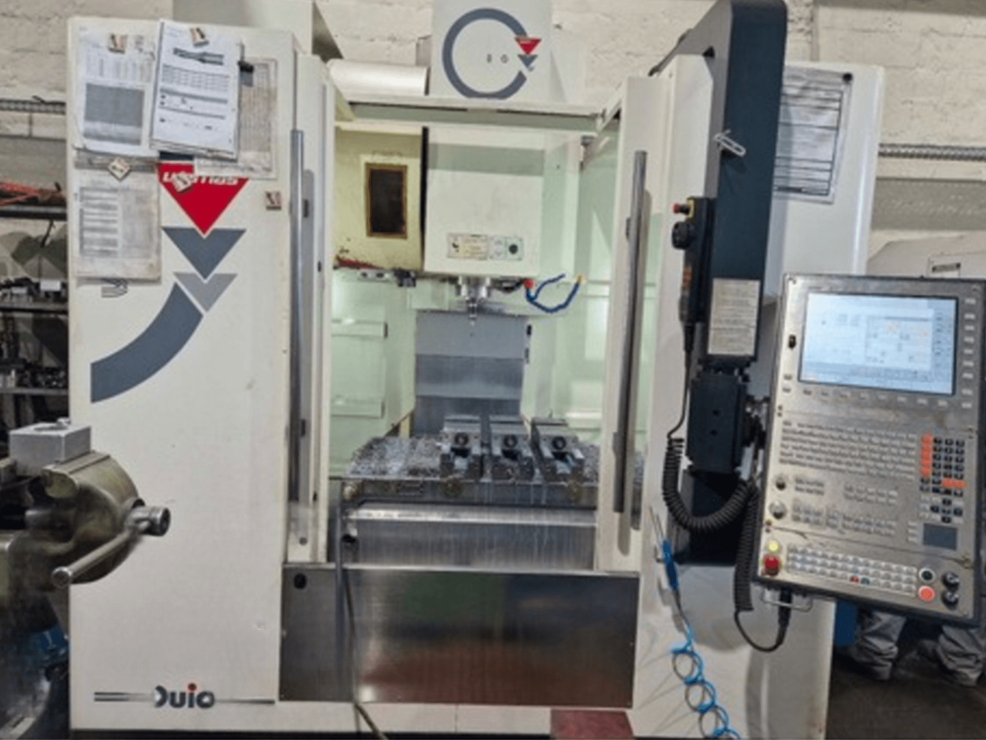 Frontvy av WEMAS VZ 860 vertikala bearbetningscenter med kontrollpanel och CNC-gränssnitt, med tillhörande papper.