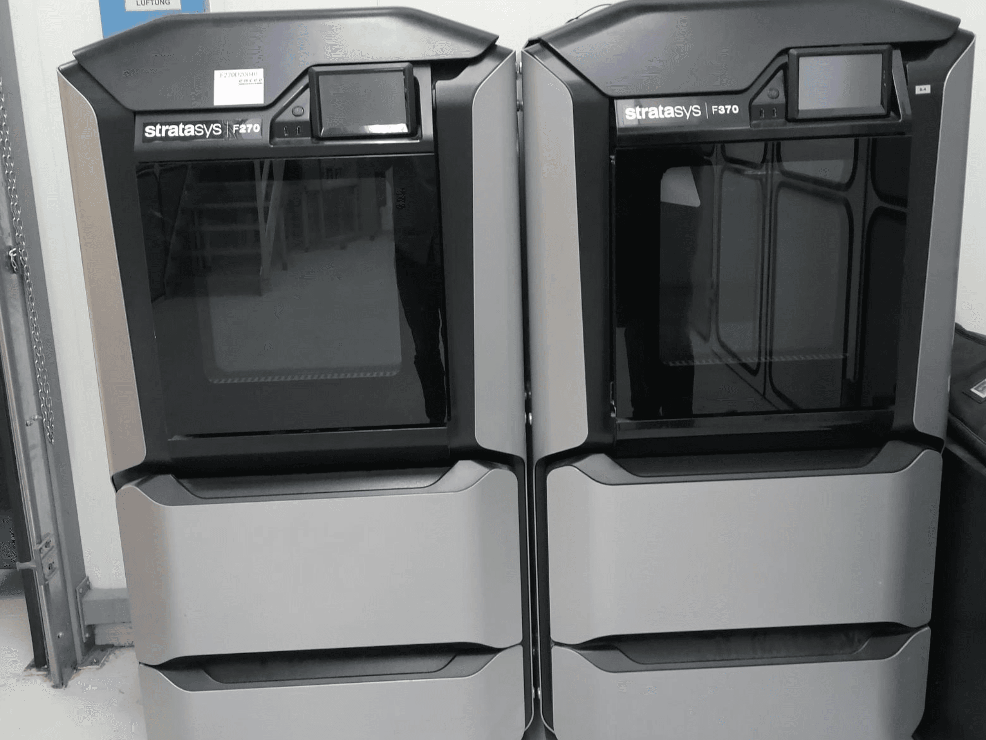 Stratasys F370 dubbla 3D-skrivare för plast visas framifrån, med elegant design i svart och silver med kontrollskärmar.